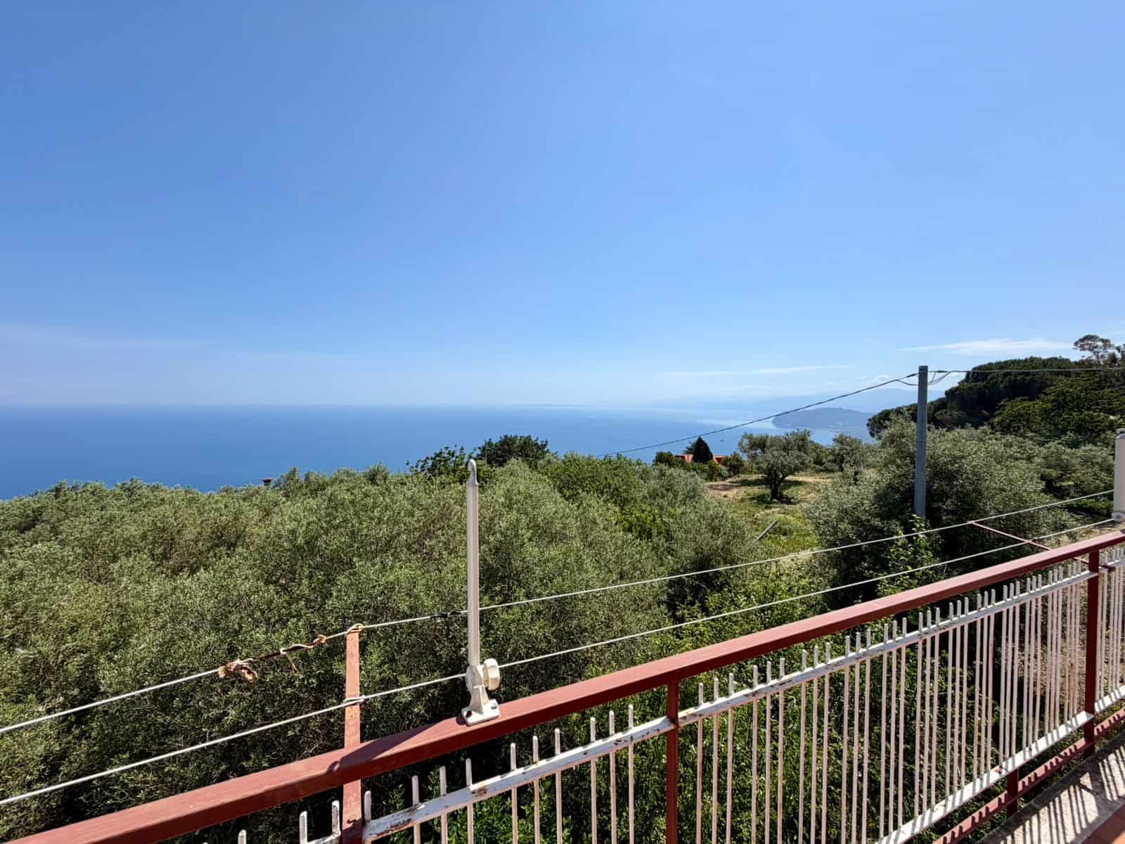 Vista panoramica mare e natura dalla terrazza di una casa in vendita, con barriere di sicurezza e paesaggio verdeggiante, ideale per immobili residenziali vicino al mare.