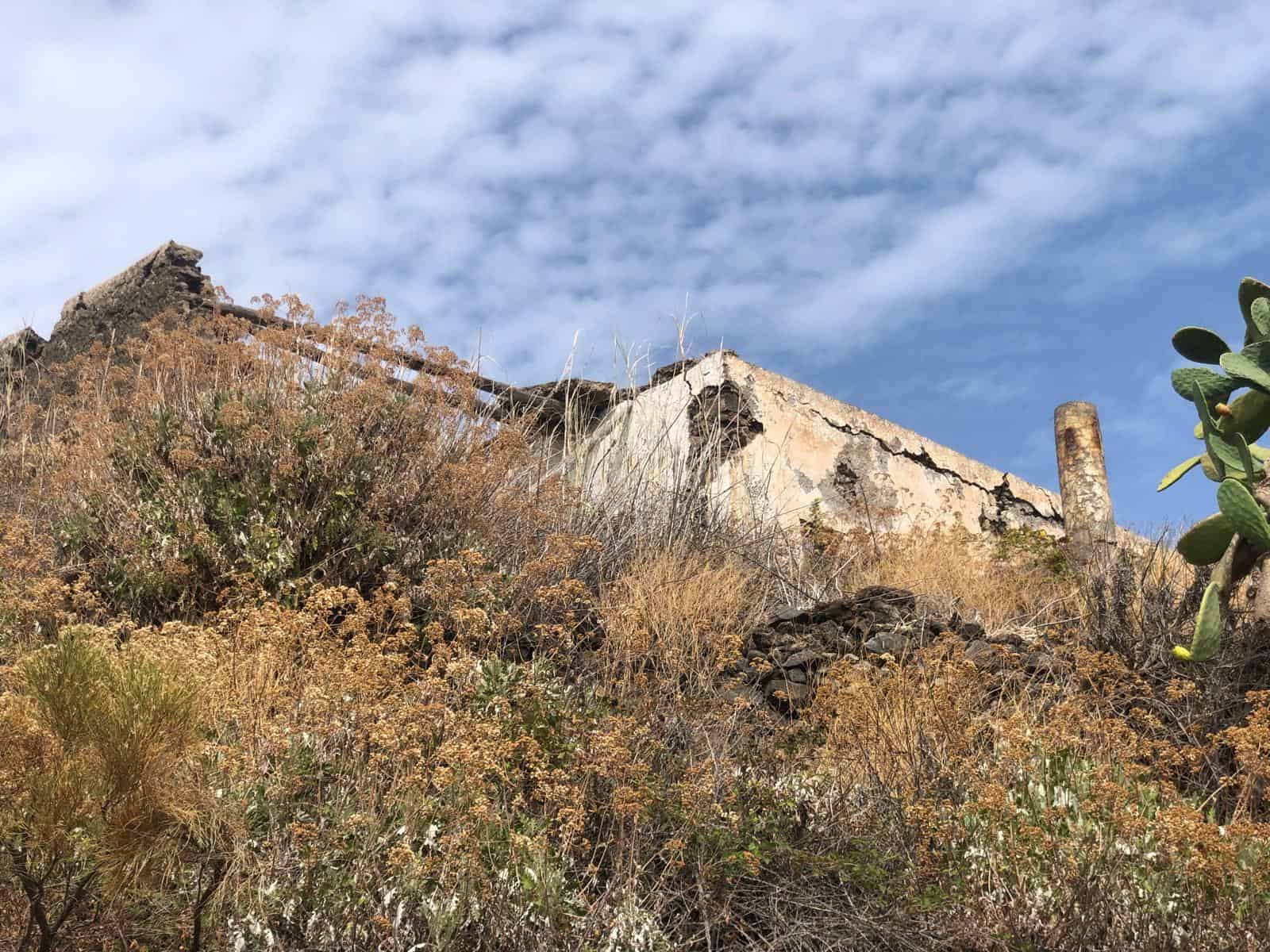 Struttura abbandonata su collina con vegetazione secca e cielo nuvoloso, scenario rurale in Italia.
