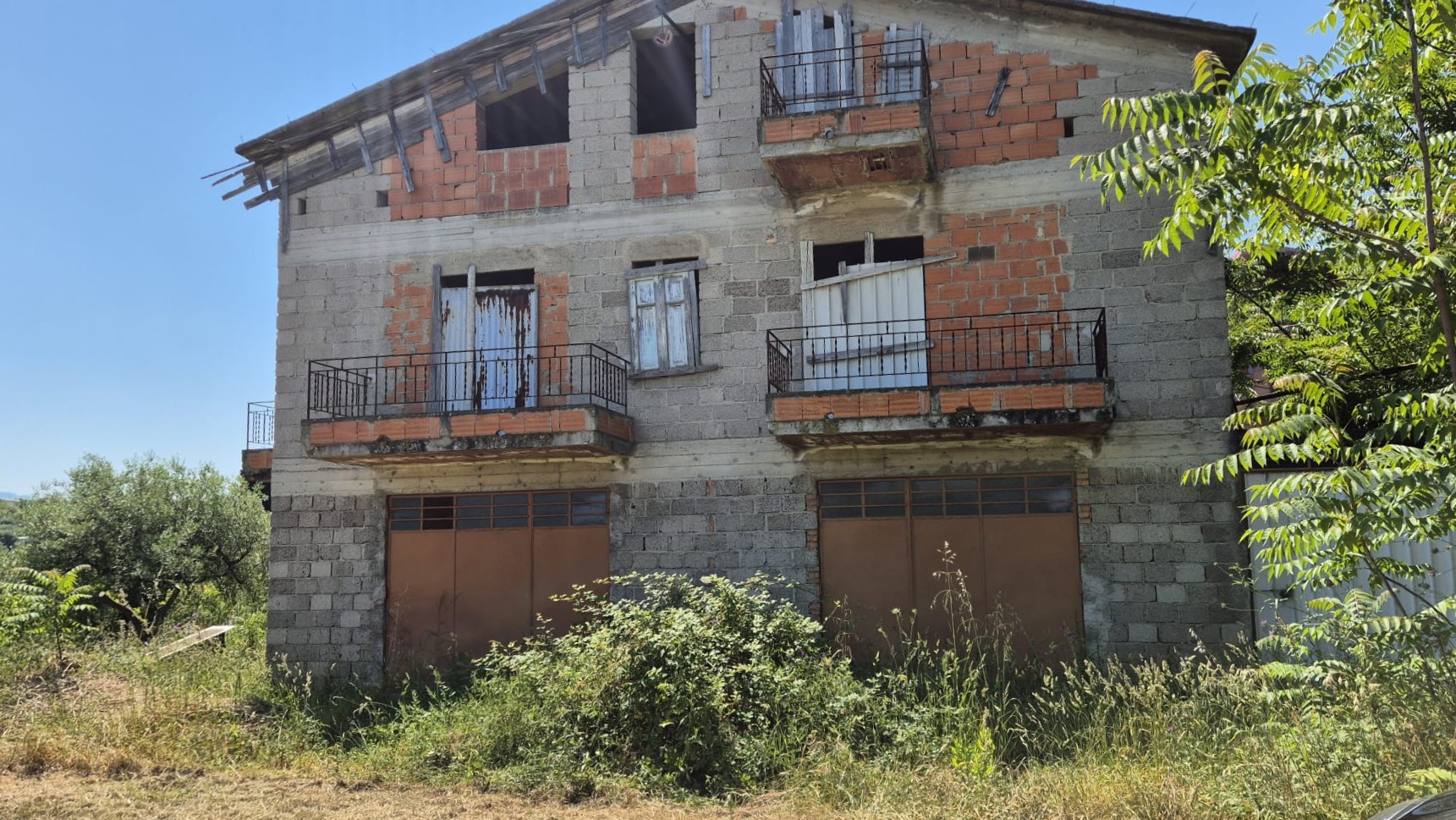 Edificio residenziale in costruzione con balconi e struttura in mattoni, situato in un'area verde, pronto per essere completato e abitato.