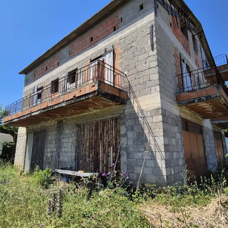Abitazione in costruzione con struttura in cemento e balconi in ferro, immersa nel verde e in un ambiente naturale, pronta per essere completata e personalizzata.