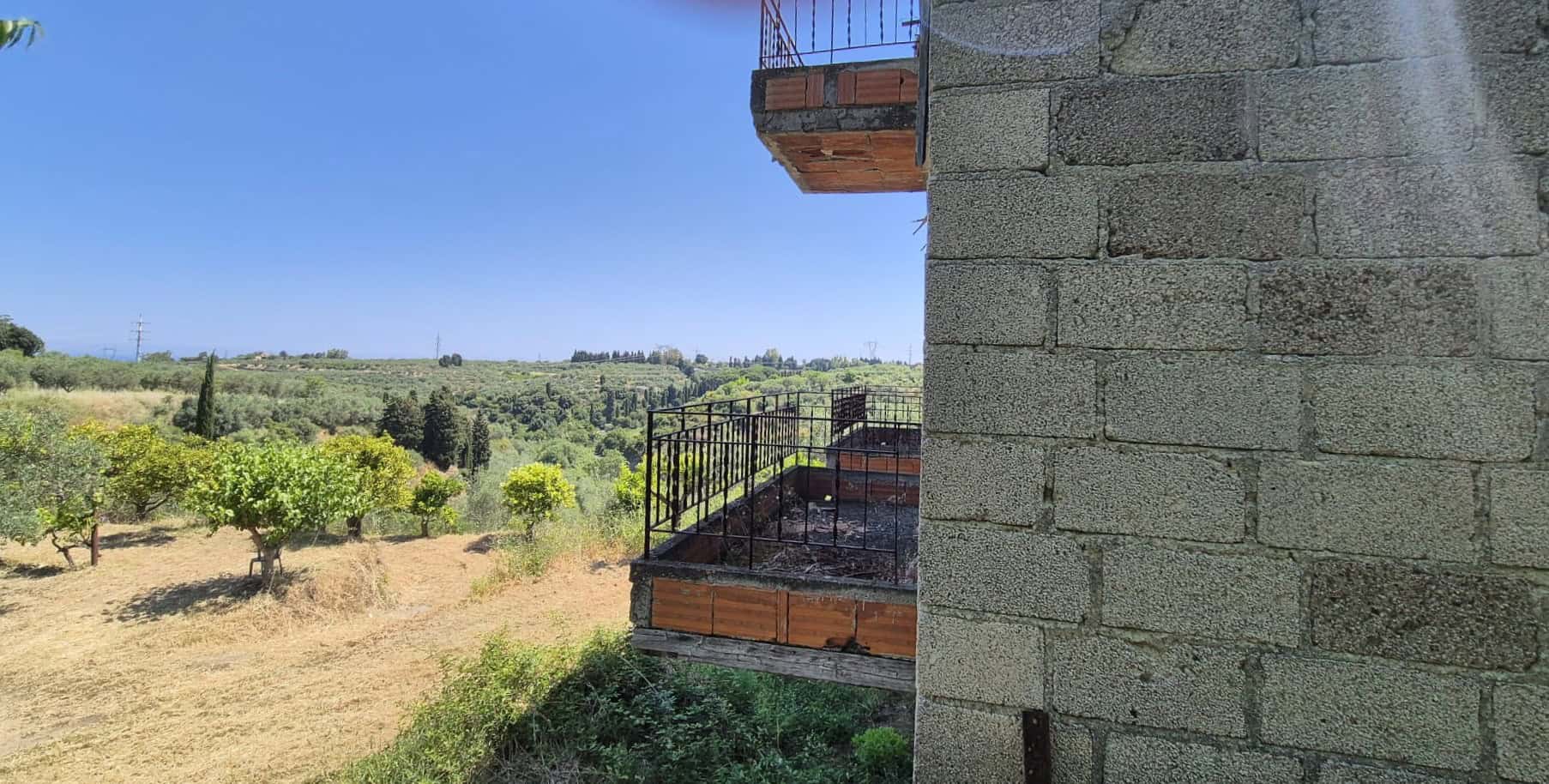 Balcone in costruzione con vista su paesaggio rurale e campagna toscana, struttura in mattoni e ferro battuto, ambiente esterno tranquillo e naturale, ideale per relax e contemplazione.