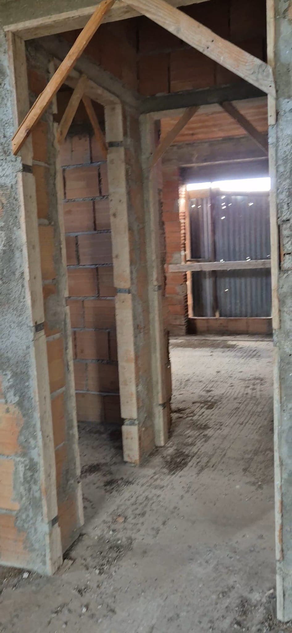 Porte interne in costruzione con struttura in cemento e mattoni, pronto per finiture e installazione di porte e infissi. L'ambiente è in fase di sviluppo, con luce naturale che filtra attraverso una f.