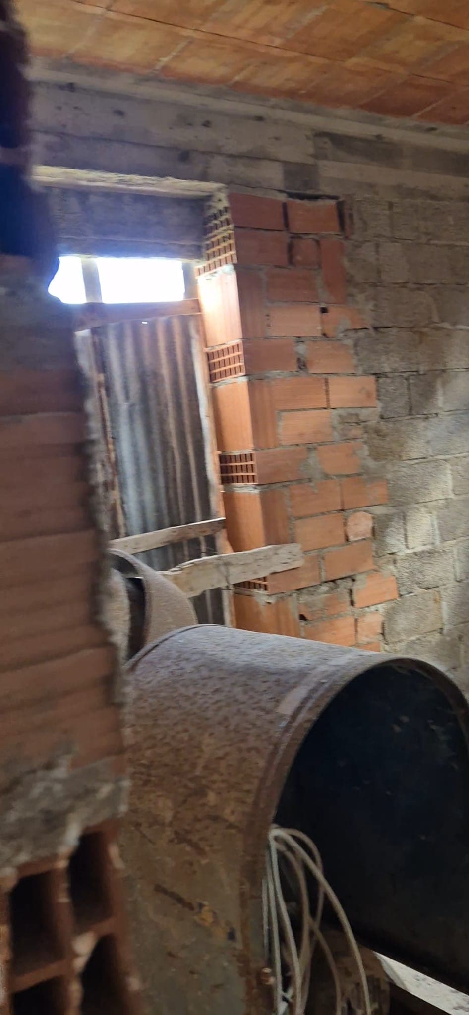 Ampia vista di un cantiere edile con pareti in mattoni e struttura in cemento, illuminato dalla luce naturale attraverso una finestra. Ideale per immagini di ristrutturazioni e lavori di costruzione.