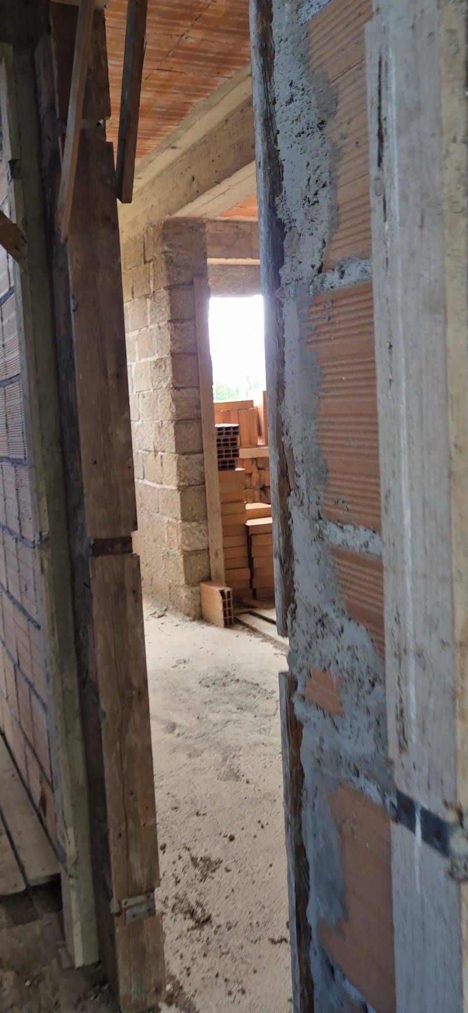 Porte in costruzione con struttura in cemento e mattoni, ambiente di cantiere con materiali edili e scaffali, vista di un edificio in fase di ristrutturazione o costruzione.