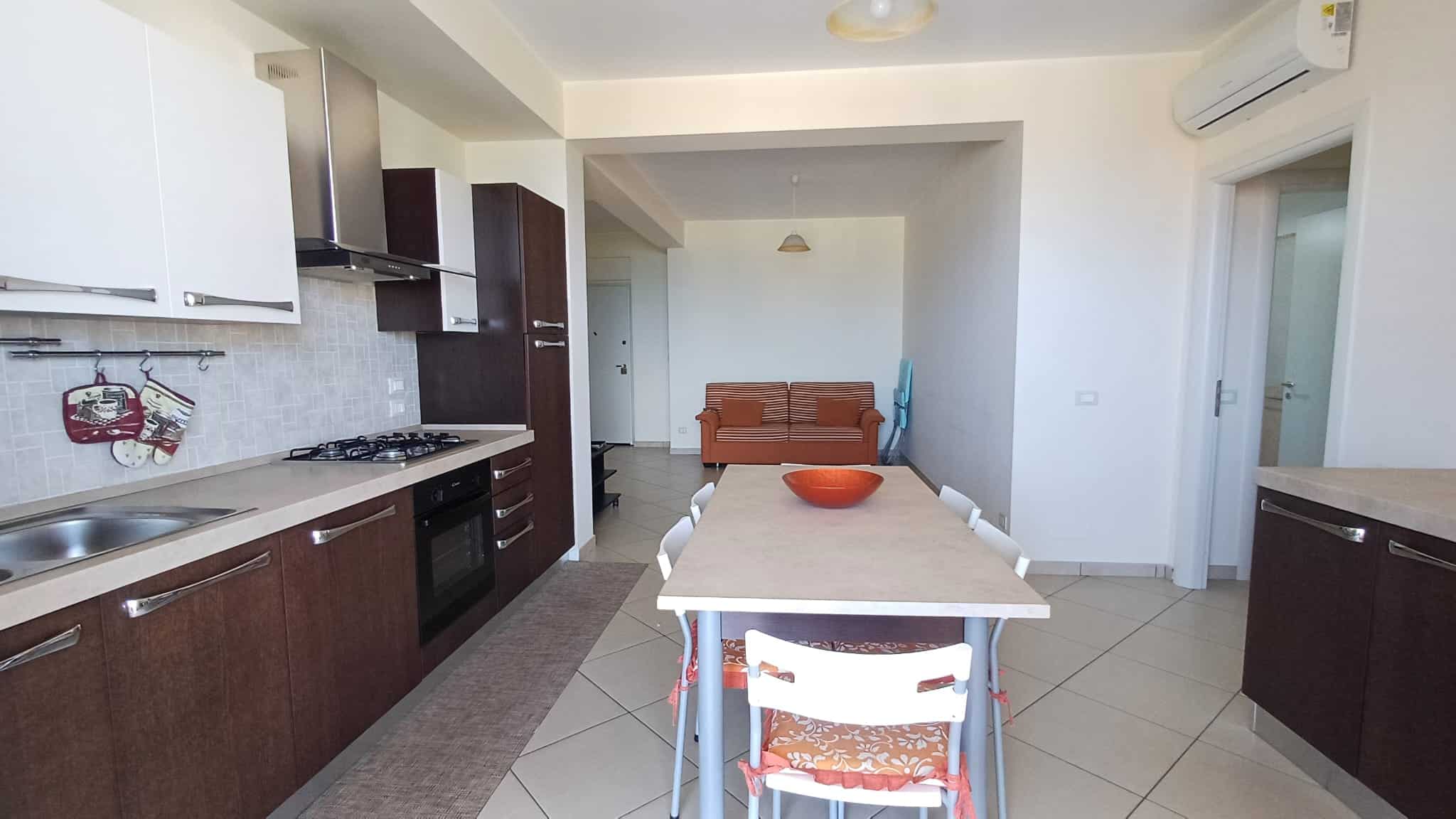 Ampio soggiorno con cucina moderna, tavolo da pranzo e zona relax, ambienti luminosi e accoglienti, ideale per vivere e condividere momenti di convivialità in un'abitazione di design.