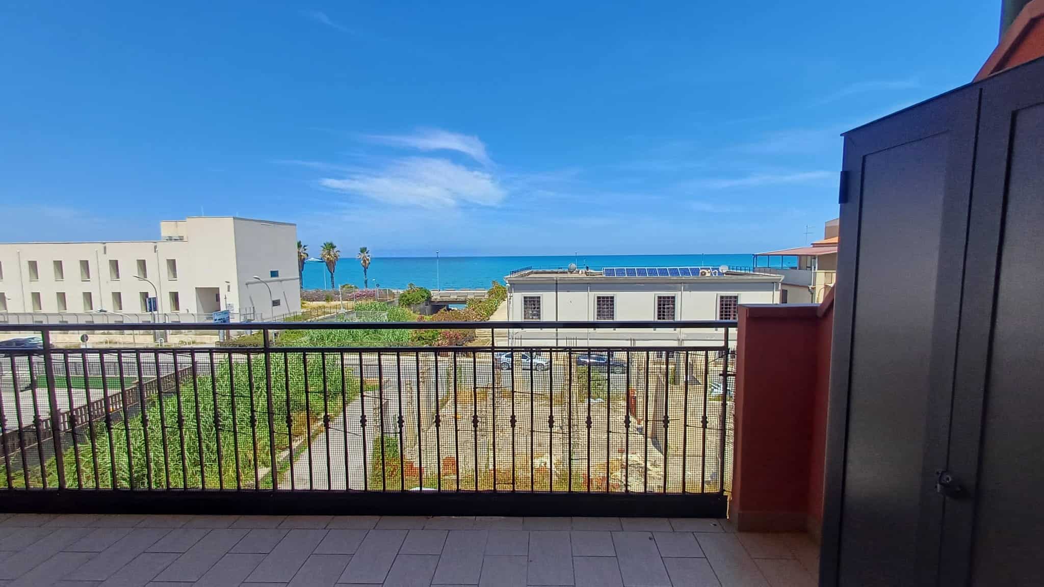 Panorama di un balcone con vista mare, edifici moderni e cielo azzurro, ideale per immobili residenziali e immobili di lusso in vendita o affitto, con attenzione a immobili vicino al mare.