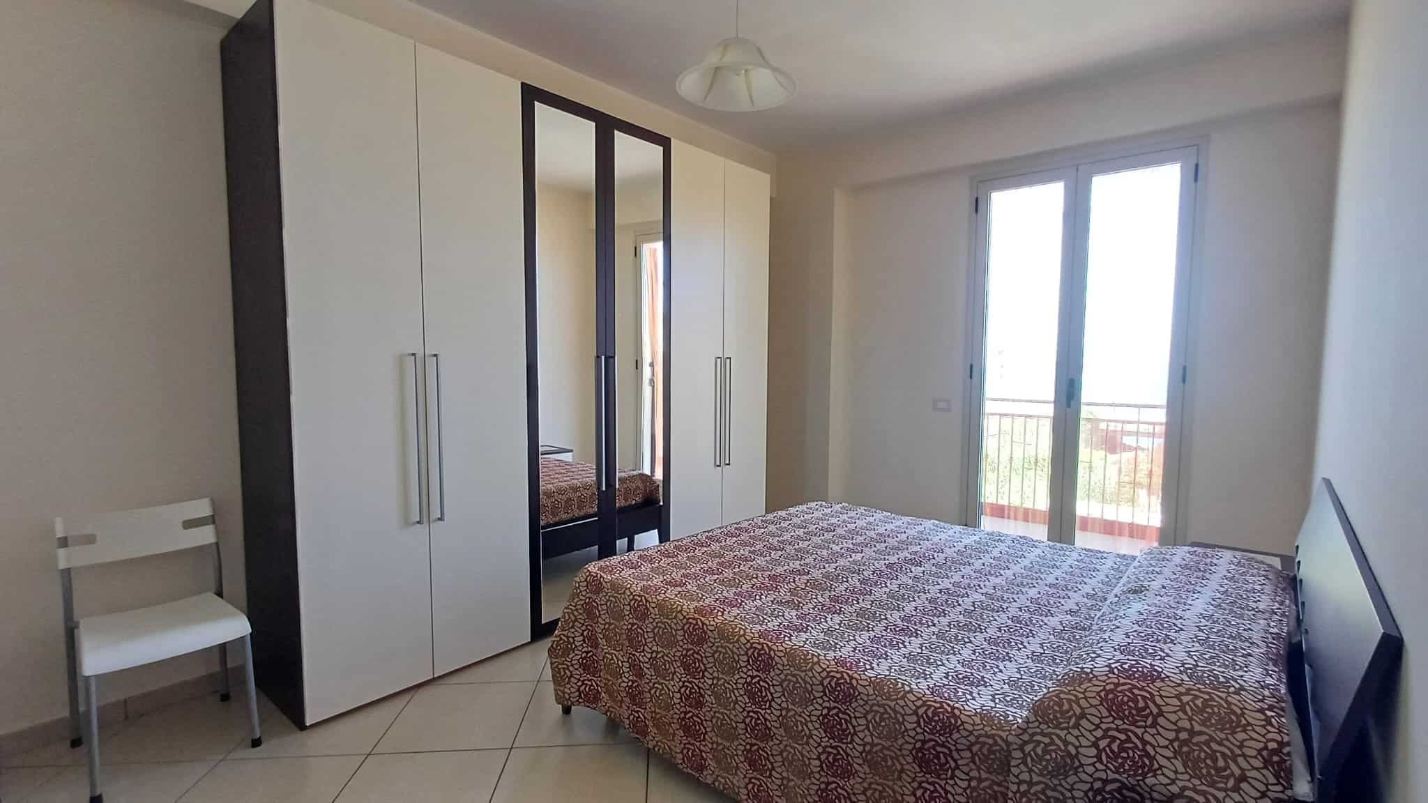 Armadio a muro con specchio e camera da letto luminosa con balcone e vista panoramica.