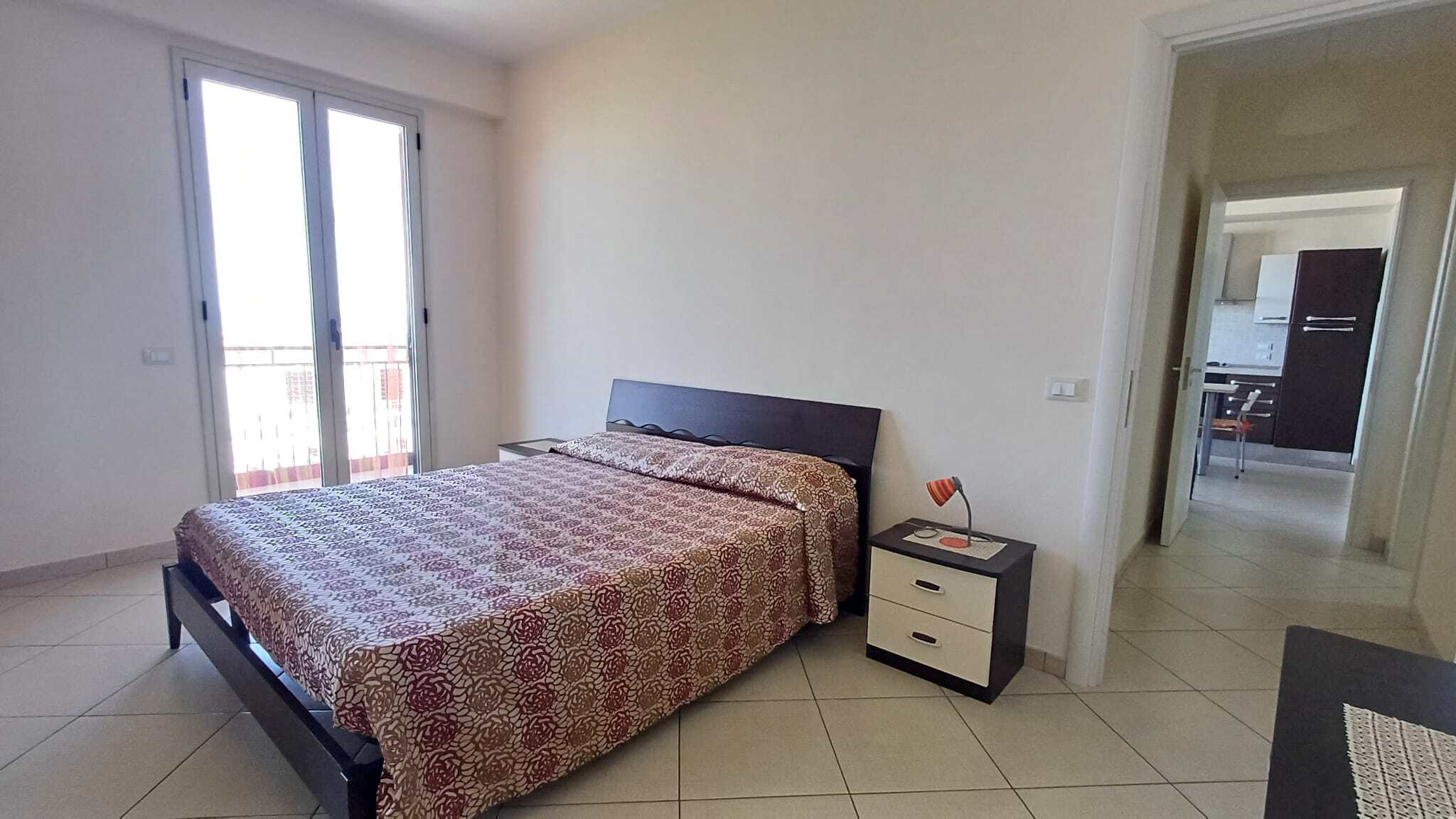 Letto matrimoniale in camera moderna con vista su balcone, arredamento elegante e luminoso, ideale per soggiorni confortevoli. Perfetto per chi cerca soluzioni di alloggio di qualità.