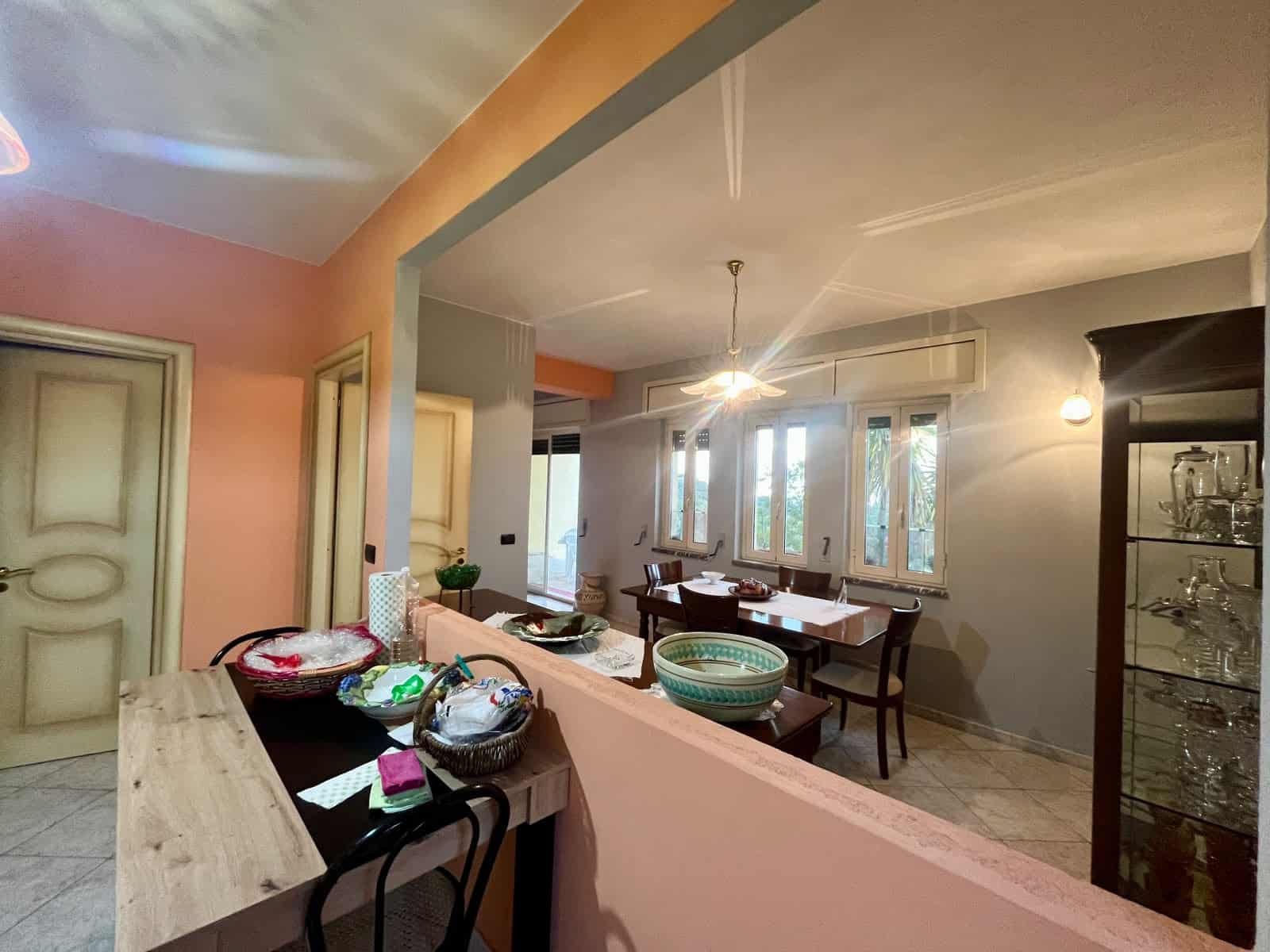 Ampia sala da pranzo luminosa con tavolo in legno, sedie comode e grandi finestre che lasciano entrare molta luce naturale, ideale per pranzi e cene in famiglia o con amici.