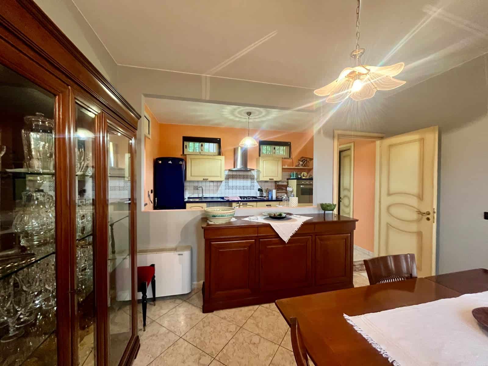 Ampia cucina con isola centrale in stile classico, dotata di elettrodomestici moderni, mobili in legno e illuminazione soffusa, ideale per cene in famiglia e incontri conviviali.