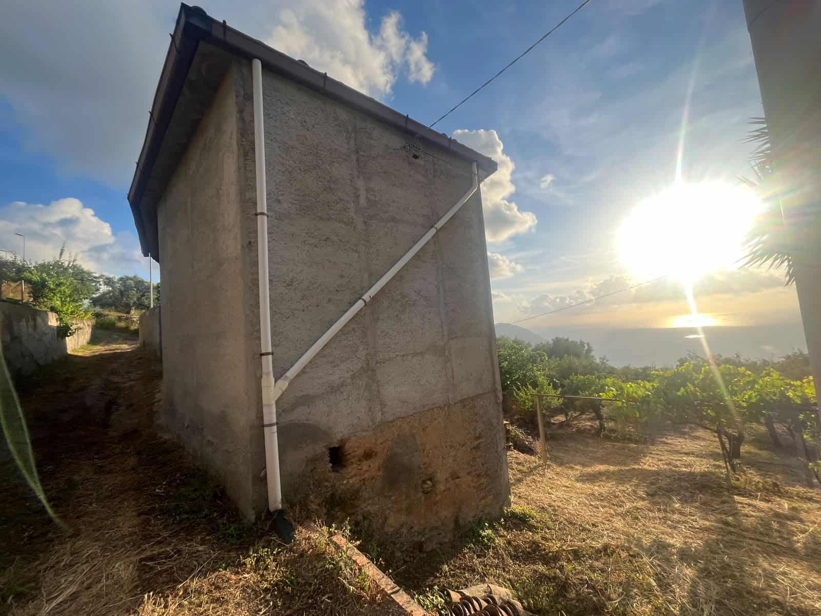 Vista laterale di una piccola casa in vendita a Gioiosa Marea con vista sul mare al tramonto.