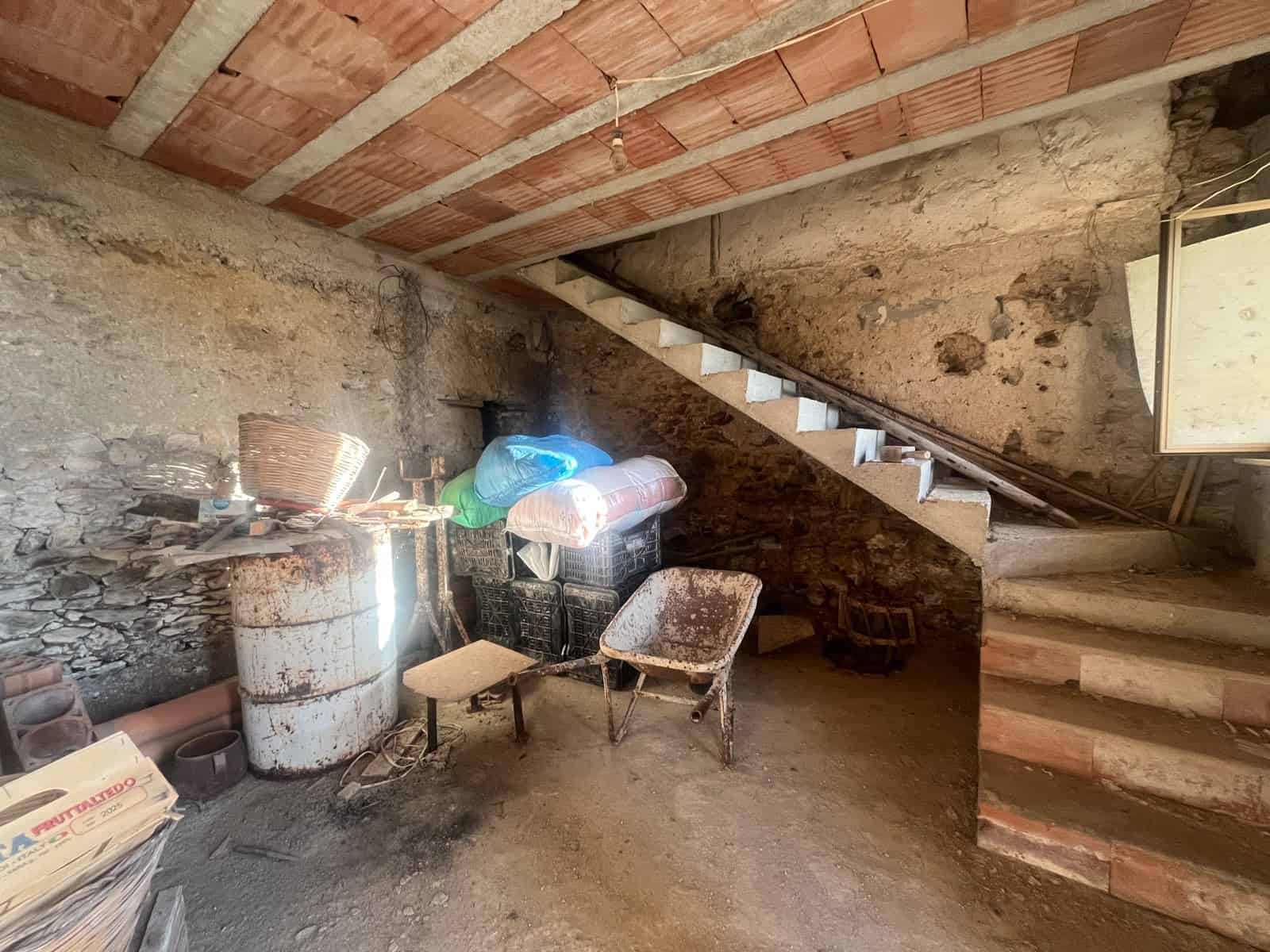 Interno di una cantina o soffitta con scaffali, sedie e materiali di deposito, in un edificio in fase di ristrutturazione.