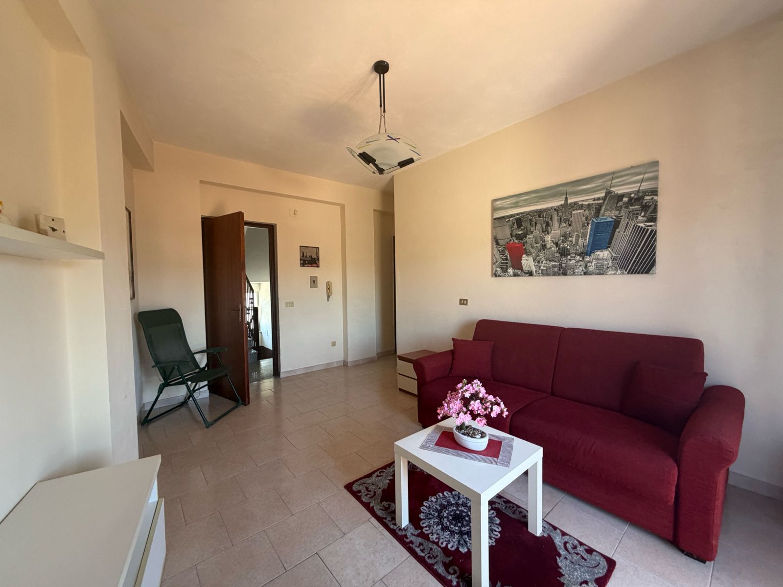Interno di un appartamento con divano rosso, tavolino e decorazioni moderne a Terme Vigliatore.
