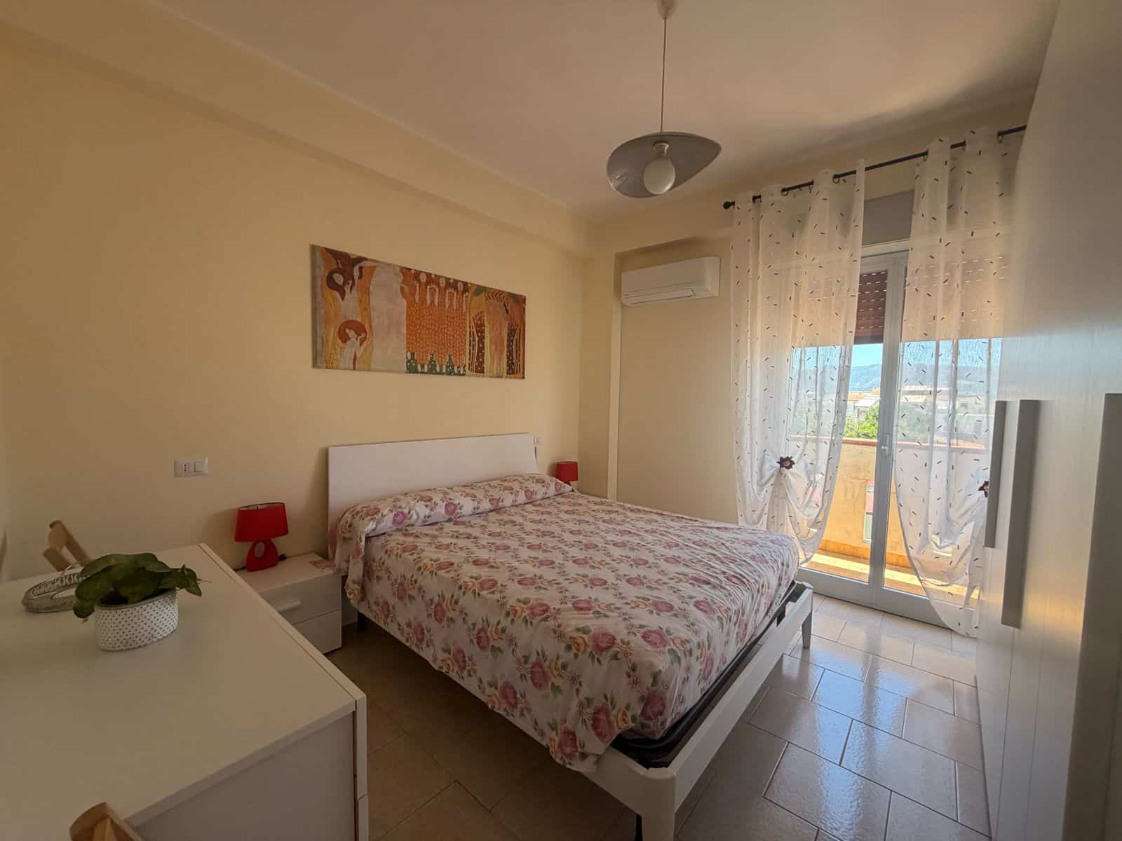 Camera da letto luminosa con letto matrimoniale, tende trasparenti e balcone con vista mare a Terme Vigliatore.