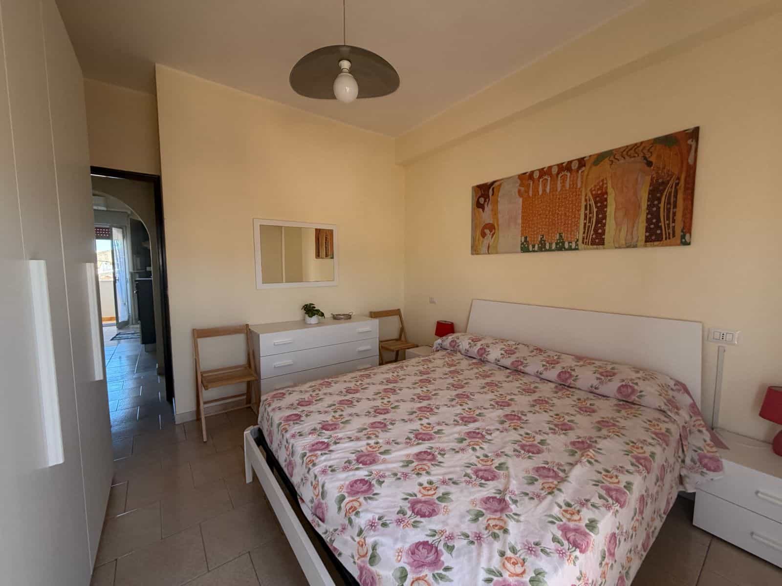 Camera da letto con letto matrimoniale, decorazioni floreali e mobili bianchi in un appartamento a Terme Vigliatore.