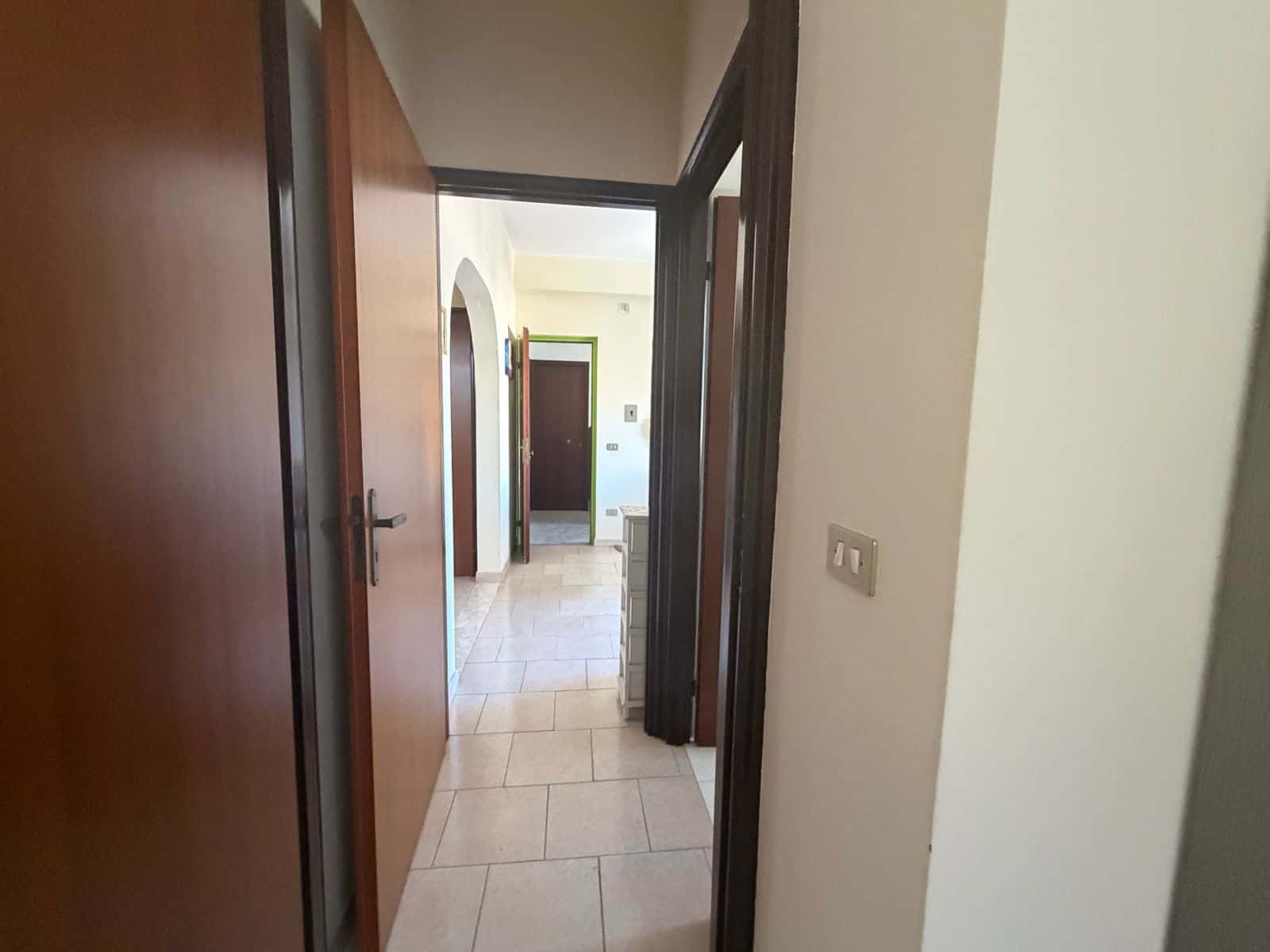 Interno di un appartamento a Terme Vigliatore con porte in legno e pavimento in piastrelle beige.