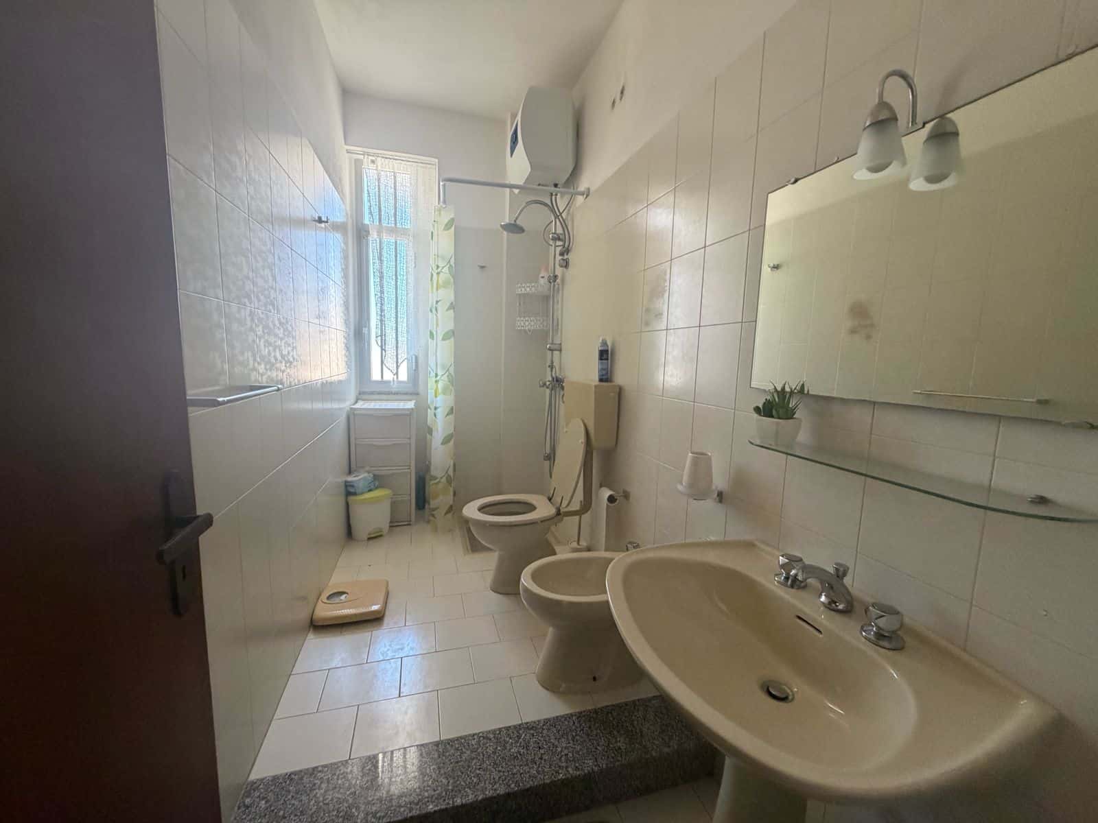 Bagno in appartamento a Terme Vigliatore con lavabo, WC e doccia, illuminato dalla luce naturale dalla finestra.