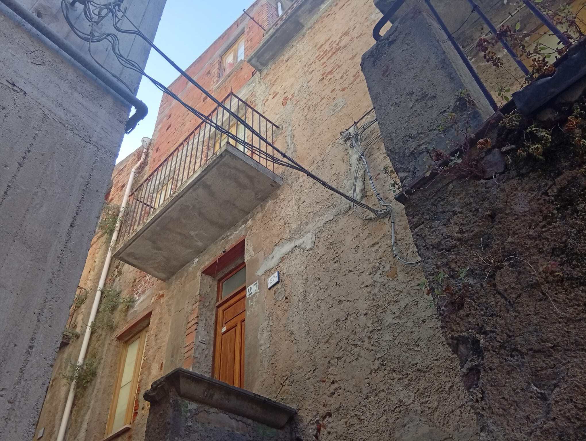 Facciata di una casa semindipendente in vendita a Ficarra, con porta in legno e balcone in ferro battuto.