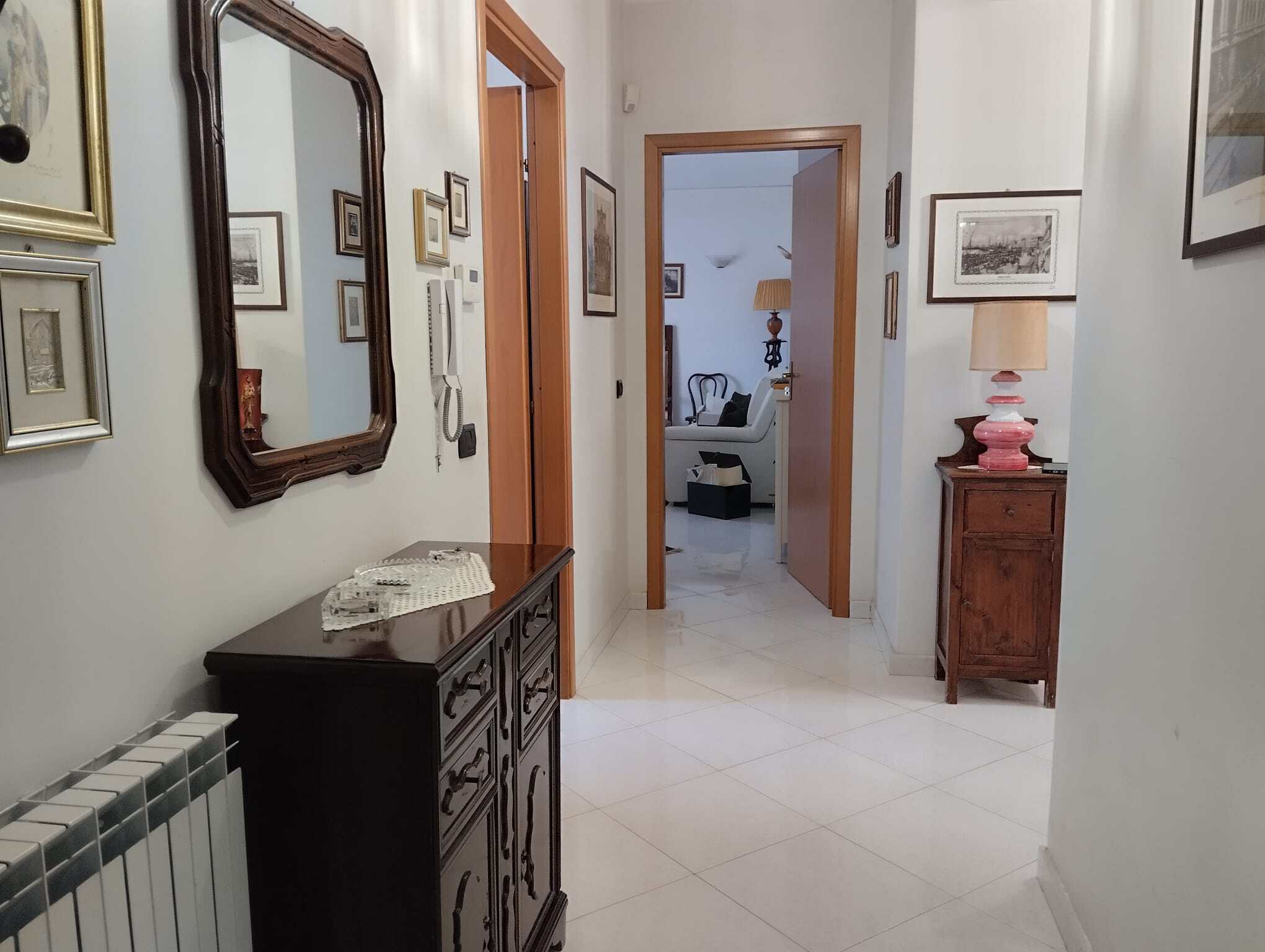Ingresso di un appartamento con pareti decorate e mobili classici, vista verso il soggiorno.