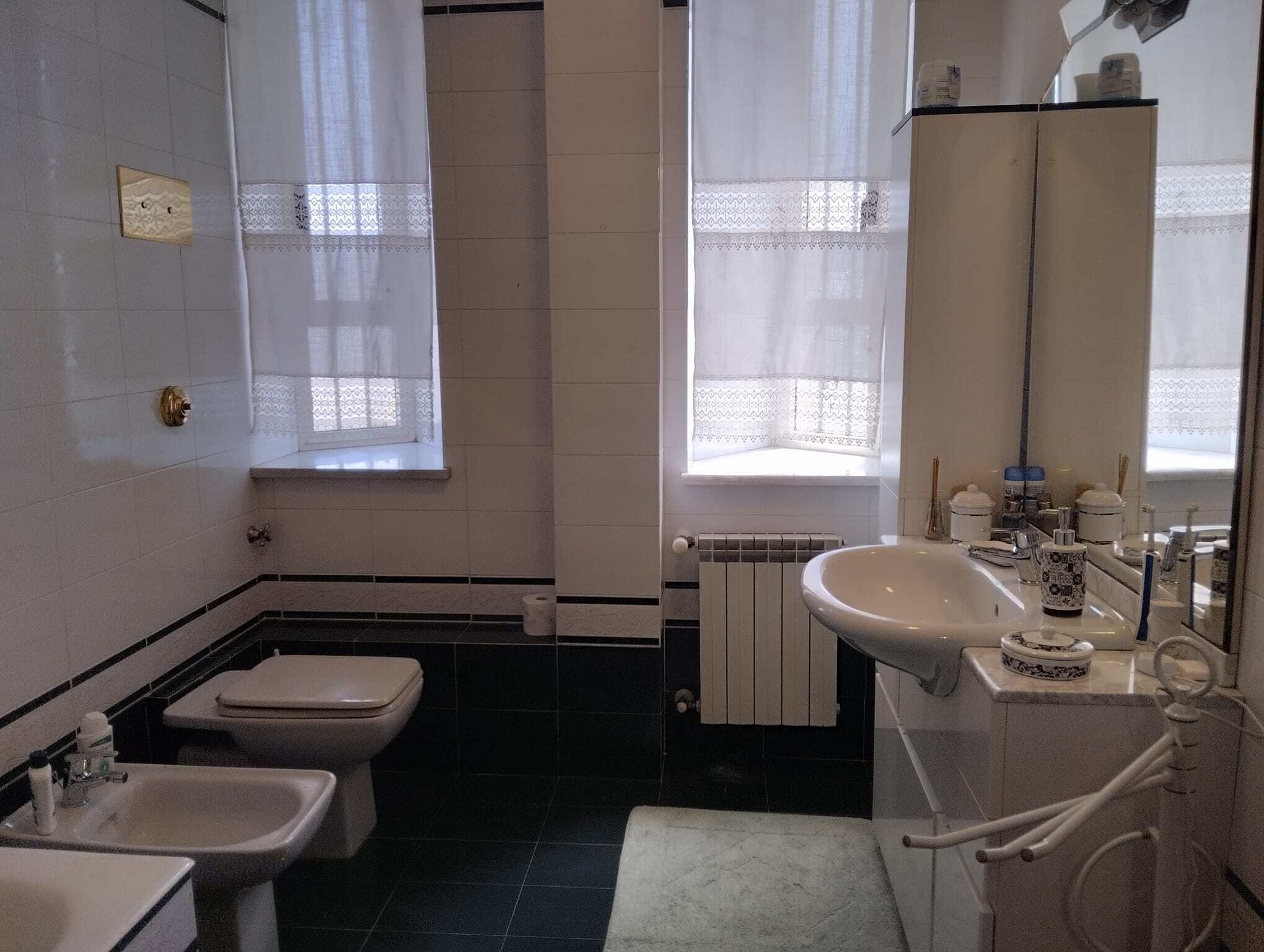 Bagno spazioso con lavabo, bidet e finestra con tende in una casa in vendita a Acquedolci, Me.