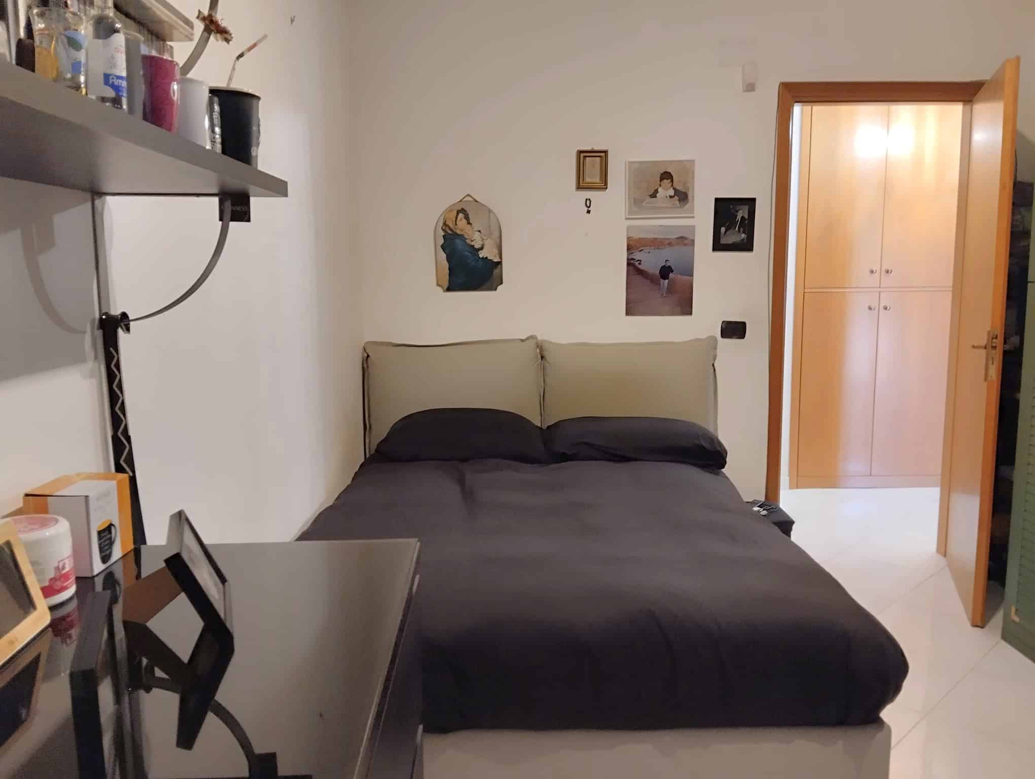 Camera che mostra una camera da letto con letto matrimoniale, pareti decorate e porta aperta verso un'altra stanza.