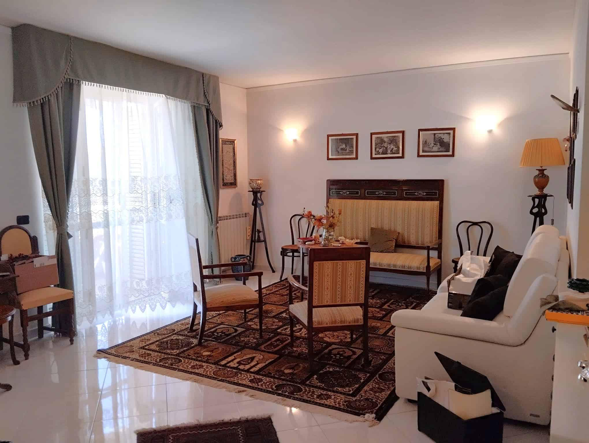Interno di un appartamento in vendita con soggiorno arredato, divani, sedie e decorazioni classiche.