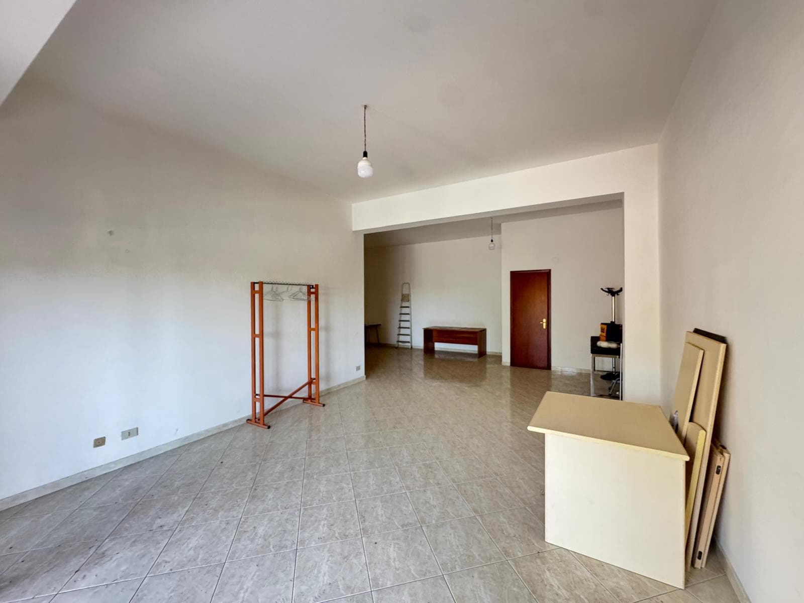 Interno di un appartamento vuoto con pareti bianche e pavimento in piastrelle, pronto per l'arredamento.