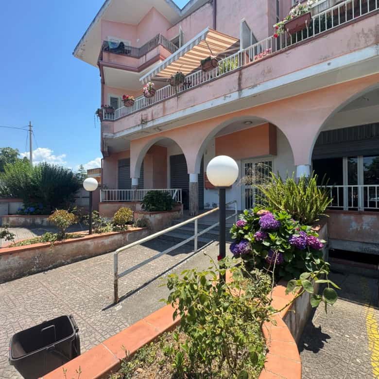 Edificio residenziale con balconi e giardino fiorito, vista esterna in una giornata soleggiata.