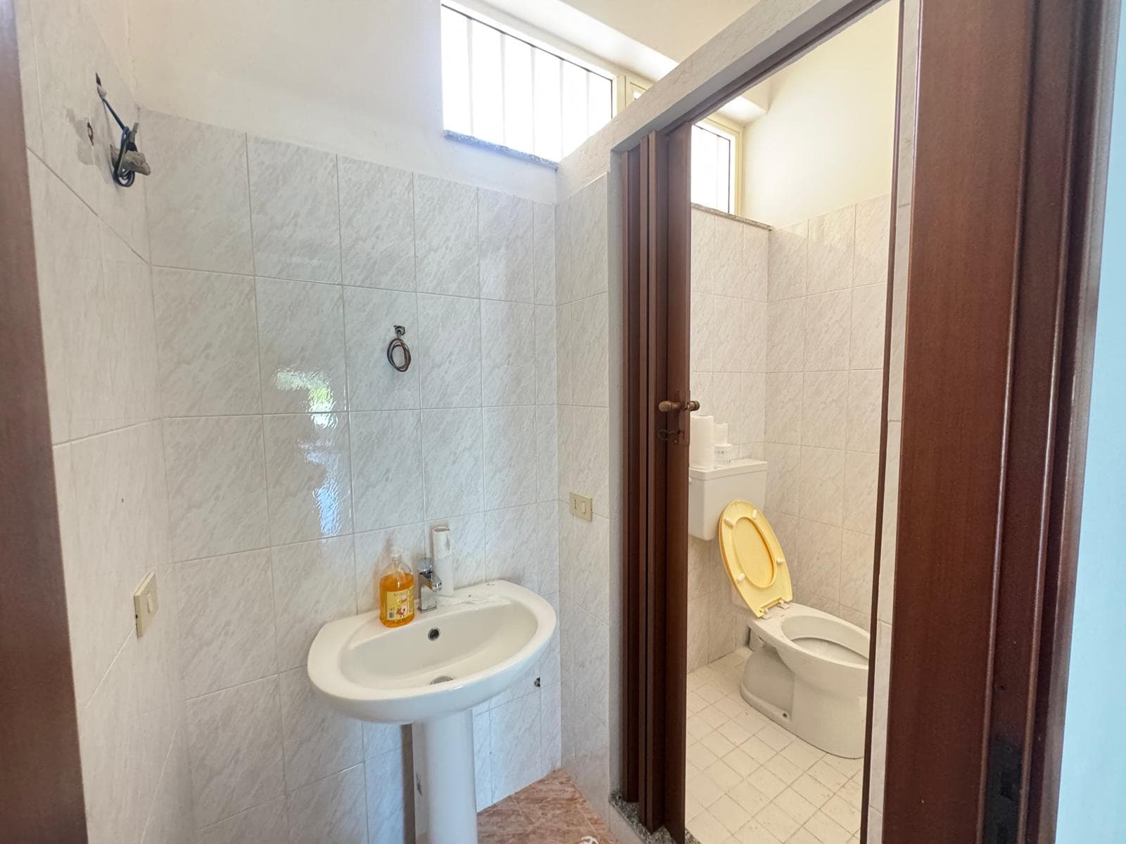 Bagno con lavabo e WC in un appartamento, spazio semplice e funzionale, illuminato dalla luce naturale.