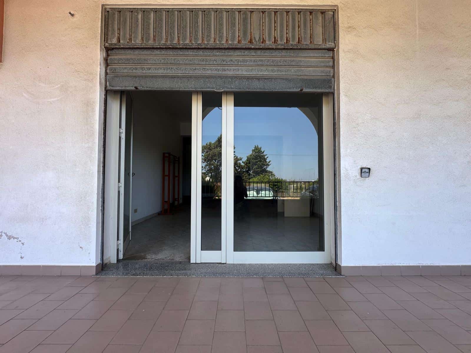 Porta finestra scorrevole in vetro con vista su balcone e paesaggio naturale, in un edificio residenziale italiano.