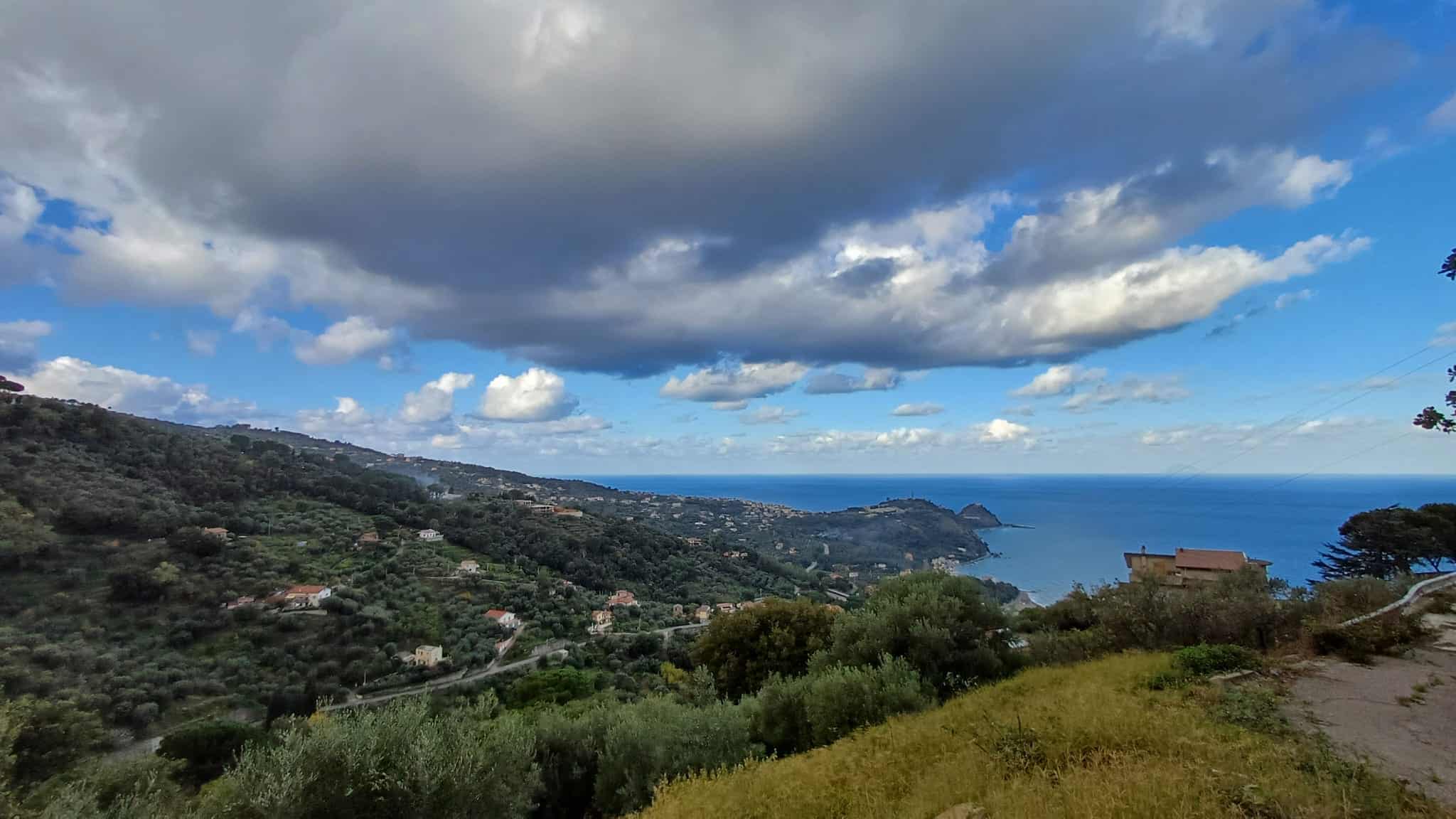Vista panoramica sulla costa di Capo d'Orlando con mare, colline e cielo nuvoloso.