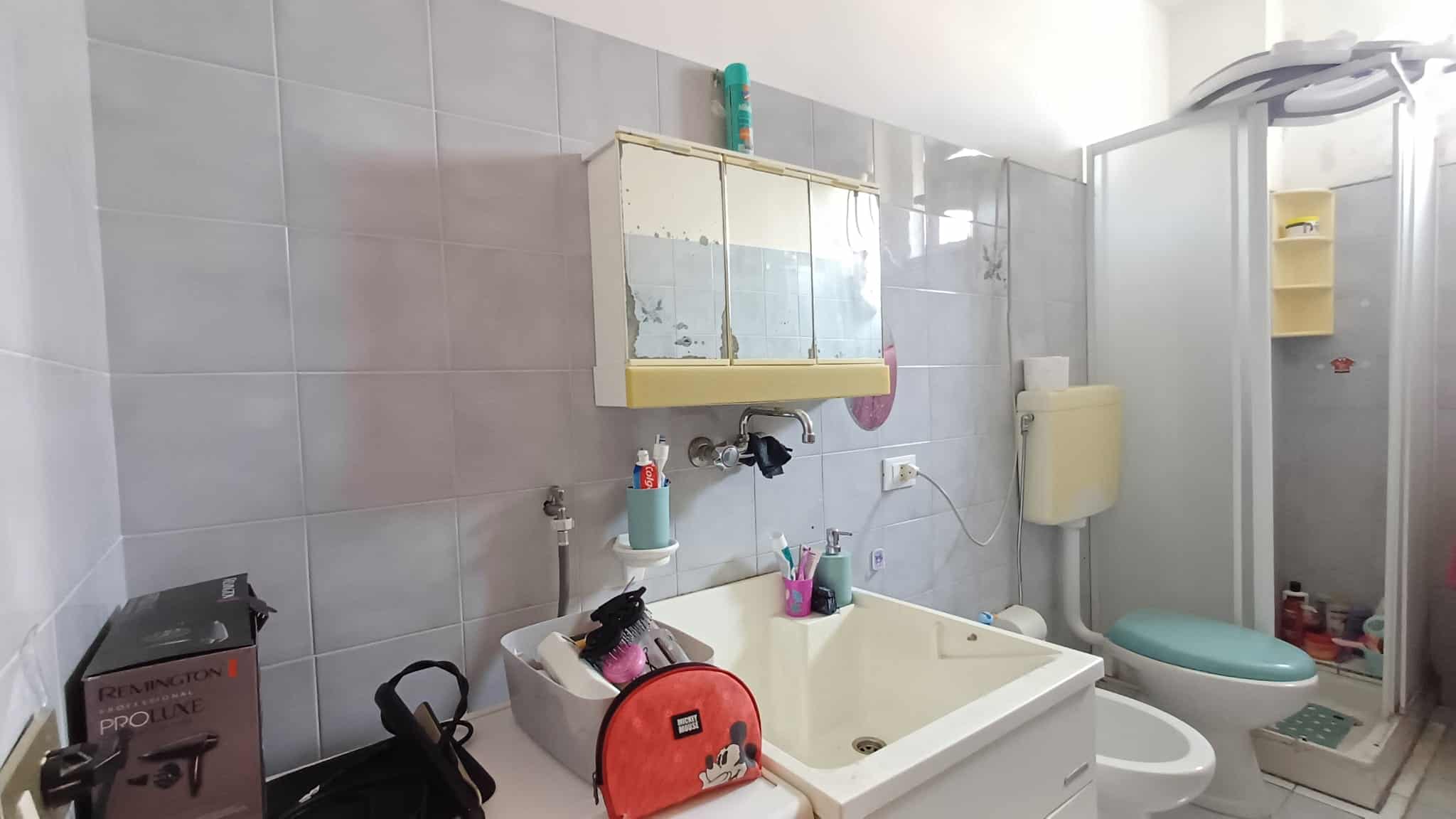 Bagno di un appartamento in vendita con lavabo, WC e doccia, arredato in stile semplice e funzionale.