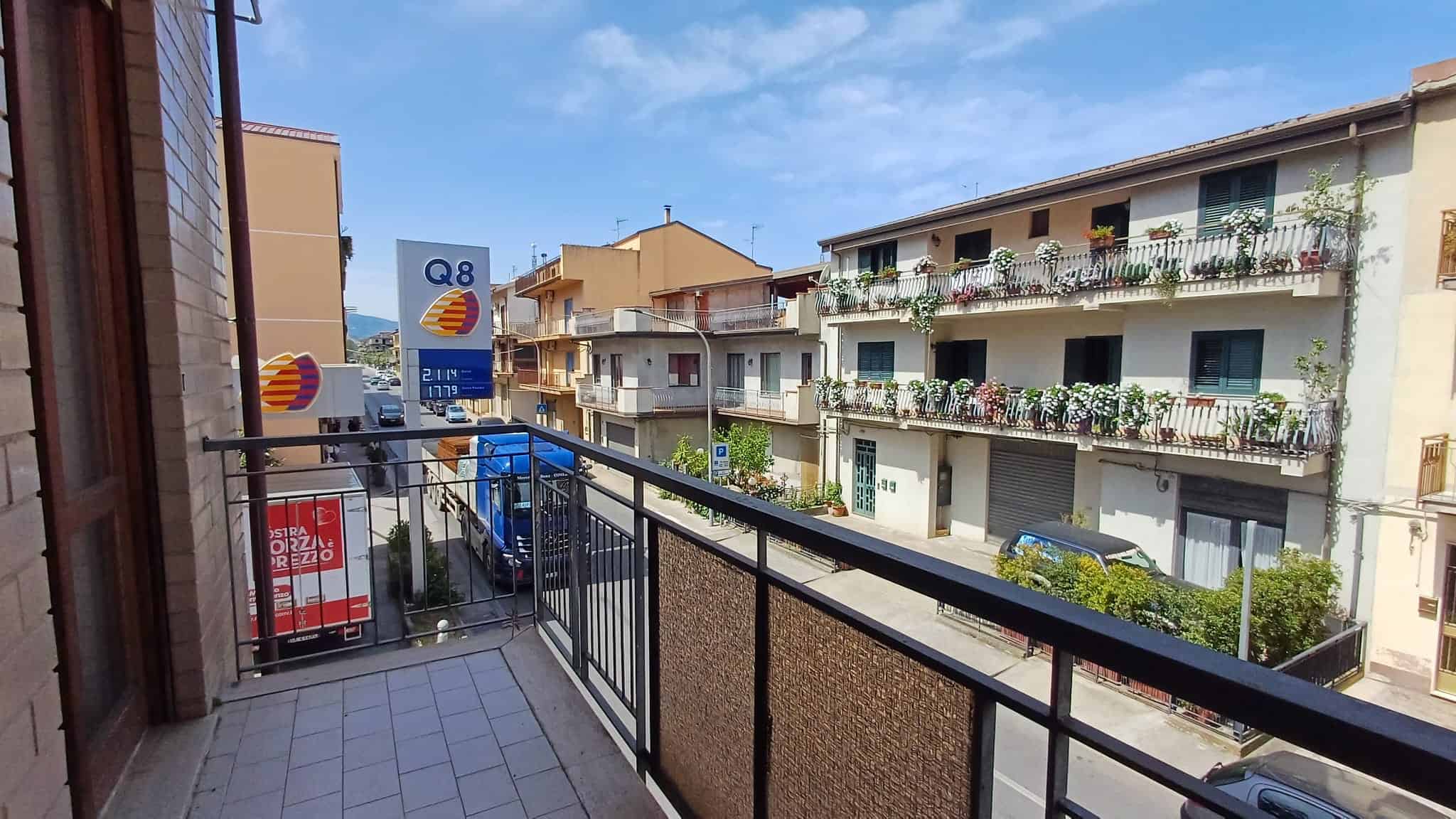 Balcone di un appartamento con vista su edifici residenziali e negozi in Via Nazionale, Rocca di Capri Leone, Me.