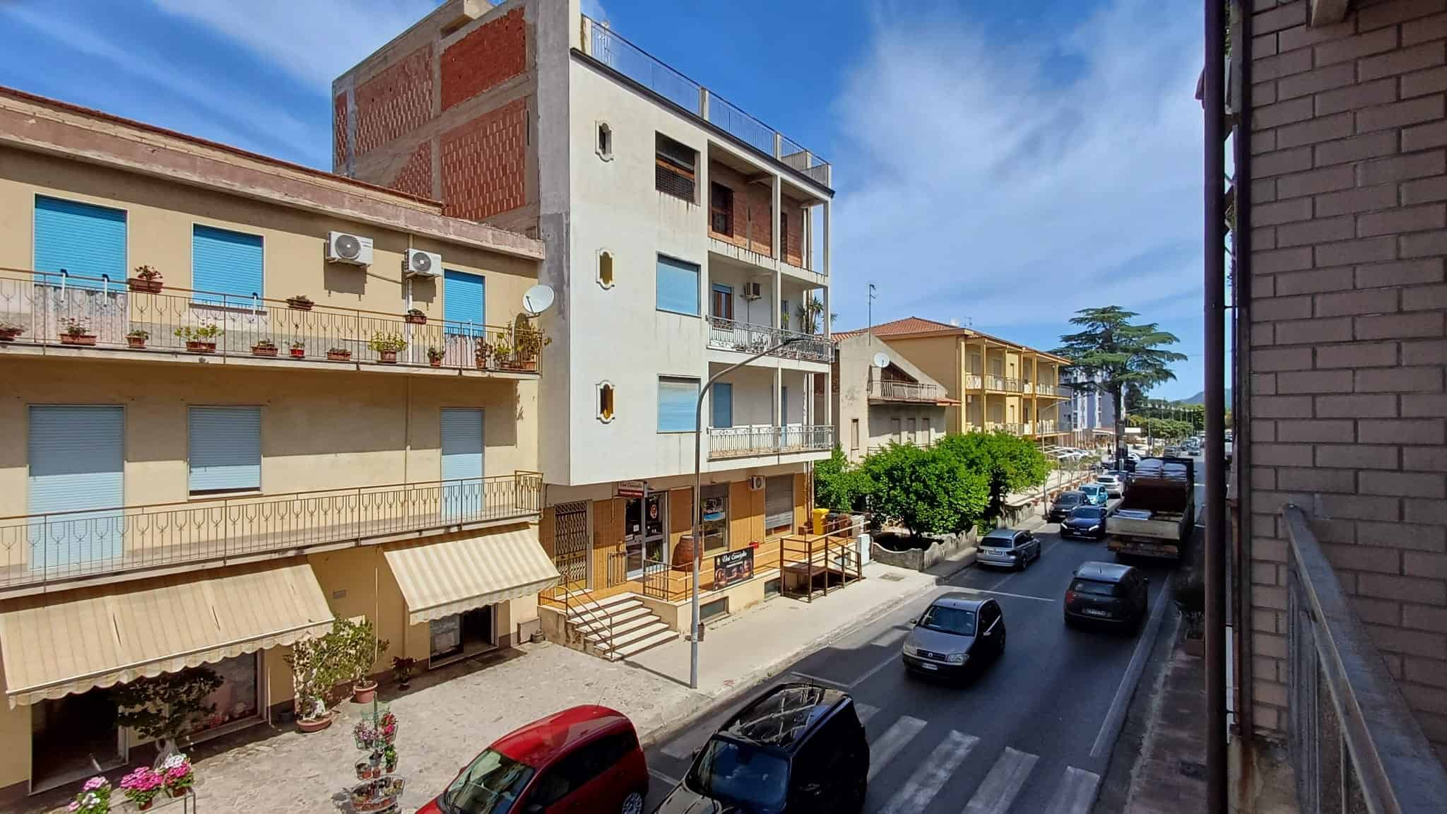 Vista di un quartiere residenziale a Rocca di Capri Leone con edifici multifamiliari e strada trafficata.