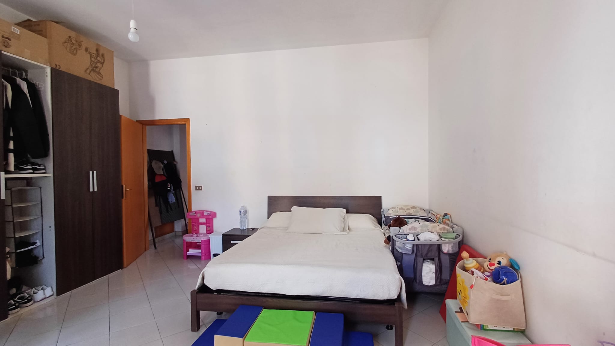 Camera che mostra una camera da letto con letto matrimoniale, armadio e vari oggetti per bambini.