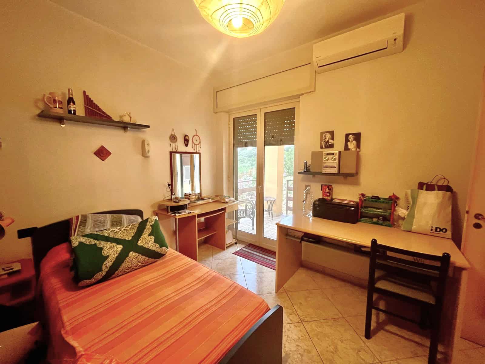 Camera da letto con balcone e aria condizionata, arredamento accogliente con letto, scrivania e scaffali, ideale per soggiorni confortevoli e rilassanti.
