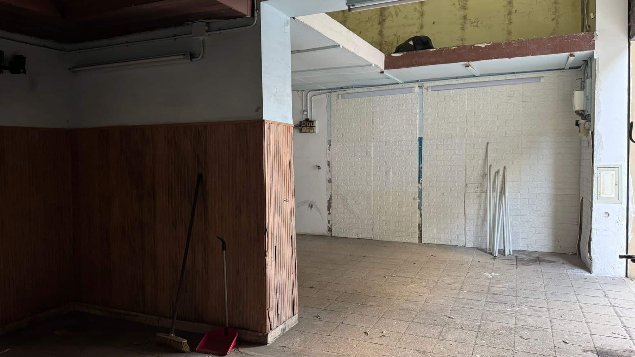 Vano garage spazioso con porta automatica e pavimento in piastrelle, ideale per parcheggio e deposito.