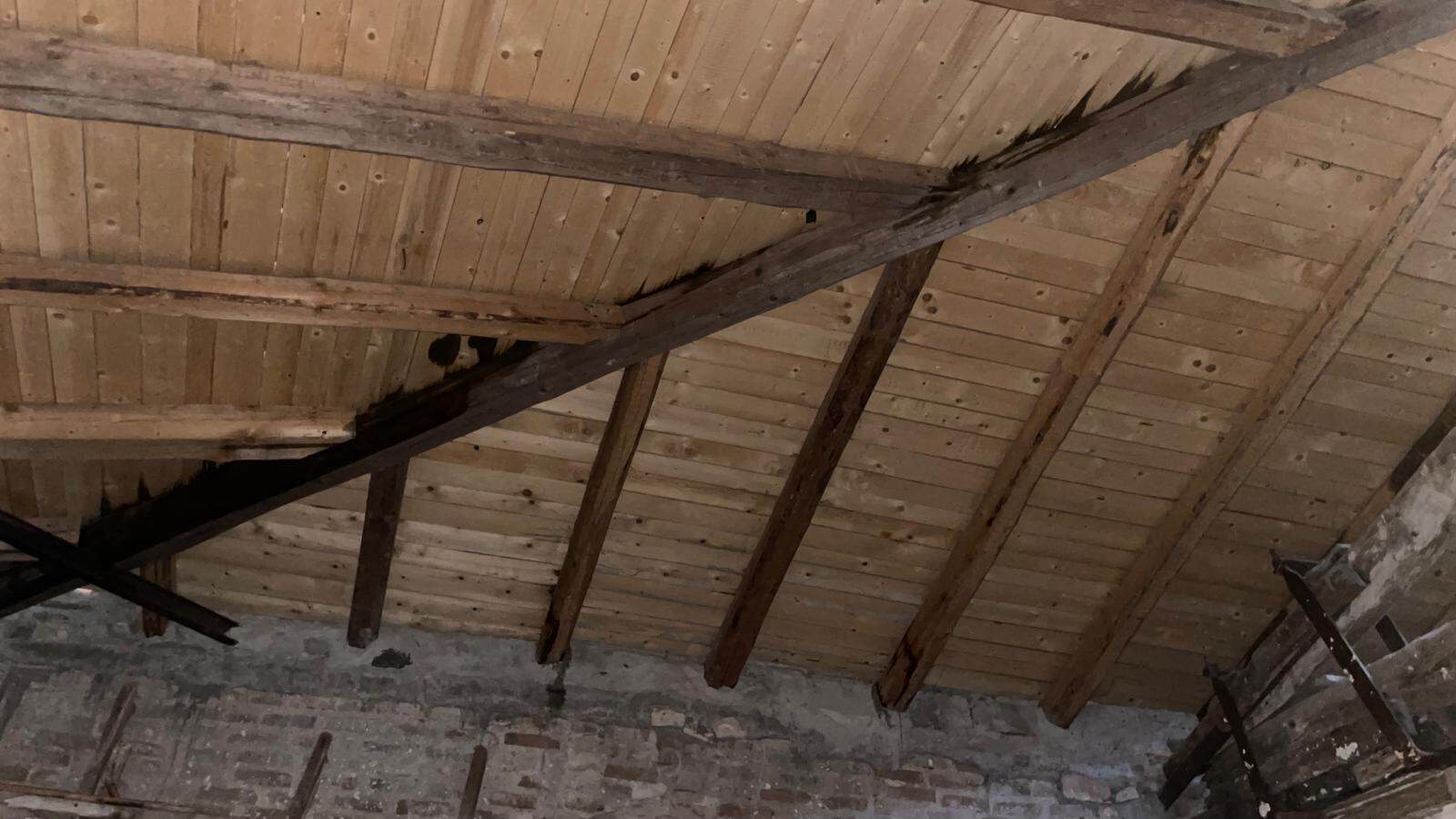 Tetto in legno con travi a vista in una casa rustica, mostra dettagli di costruzione tradizionale e materiali naturali. Perfetto per immagini di ristrutturazioni e design di interni in stile rustico.