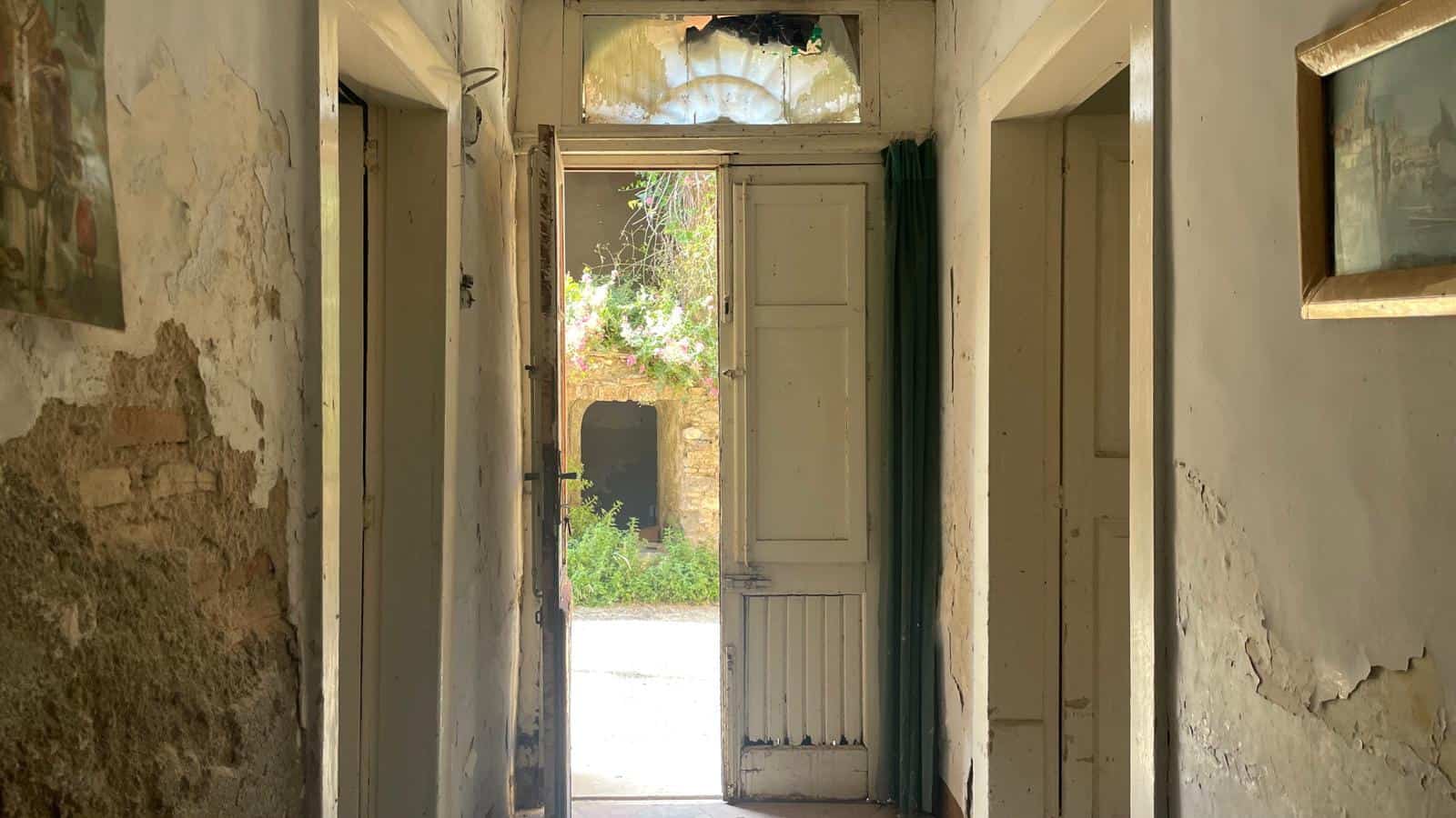 Porta in legno antica in un ingresso rustico con pareti usurate e dettagli vintage.