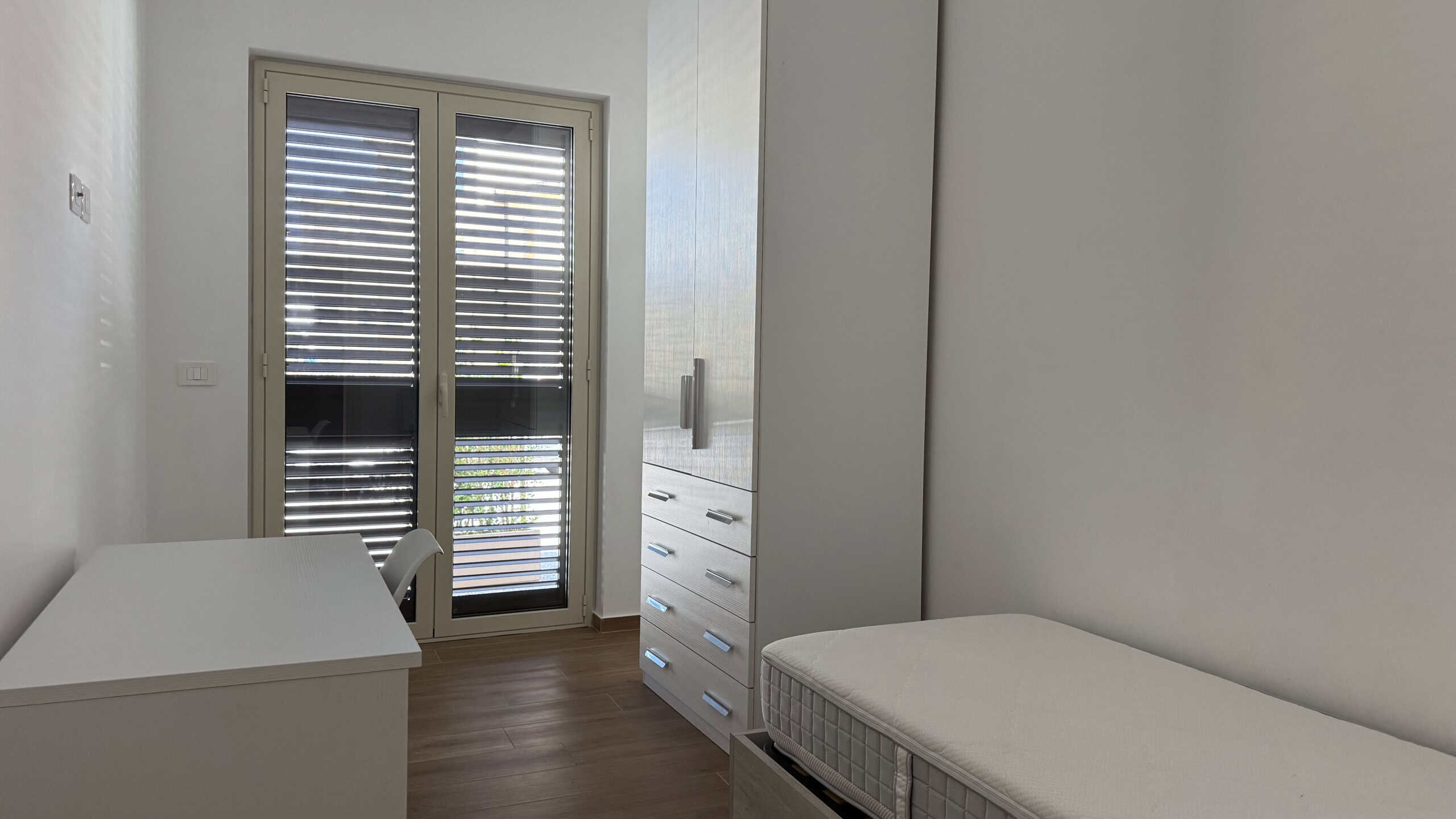 Camera singola con balcone, arredi moderni e ambiente luminoso, ideale per soggiorni confortevoli.