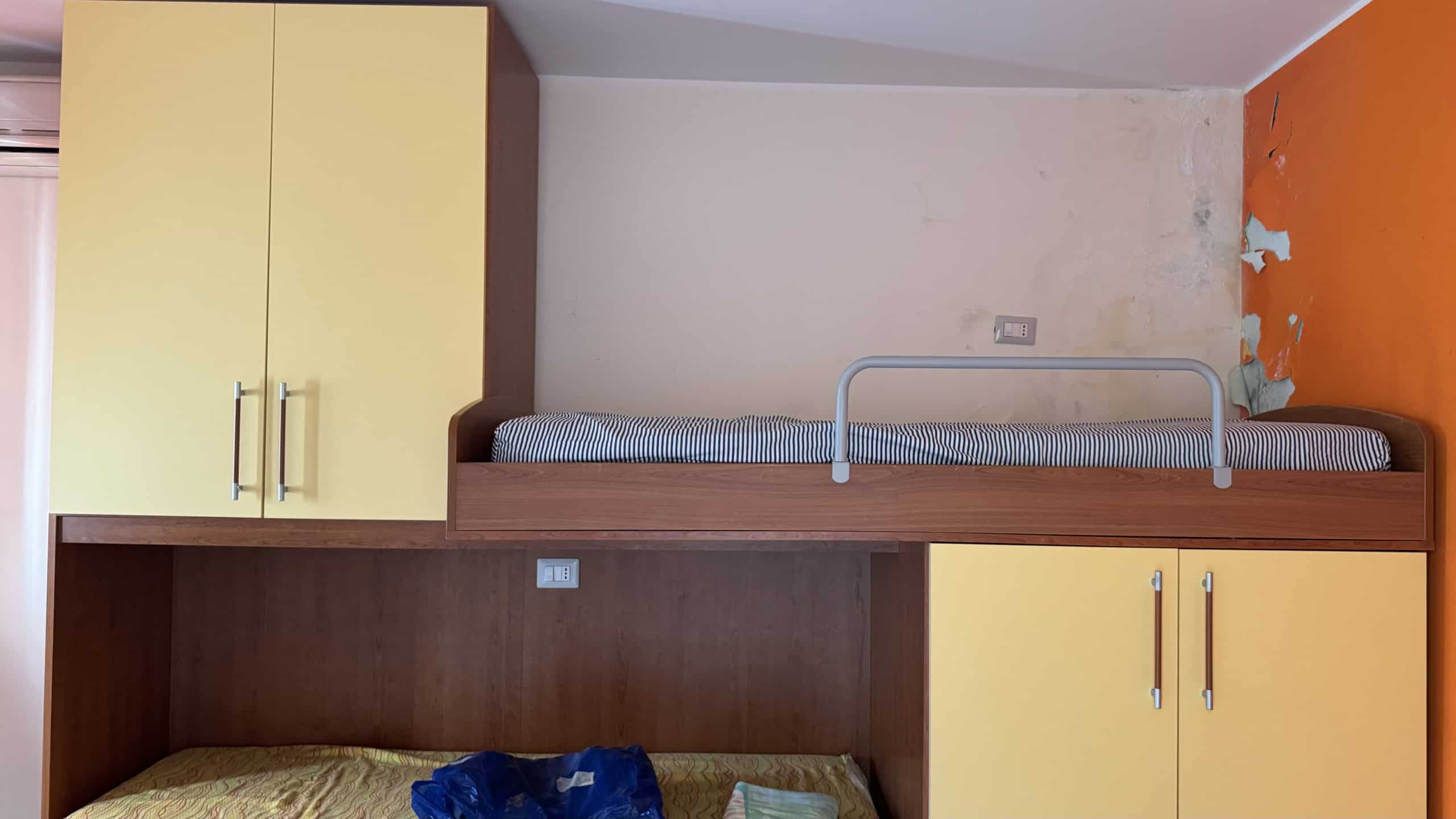 Letto a soppalco con spazio di archiviazione e armadi gialli in una stanza moderna.