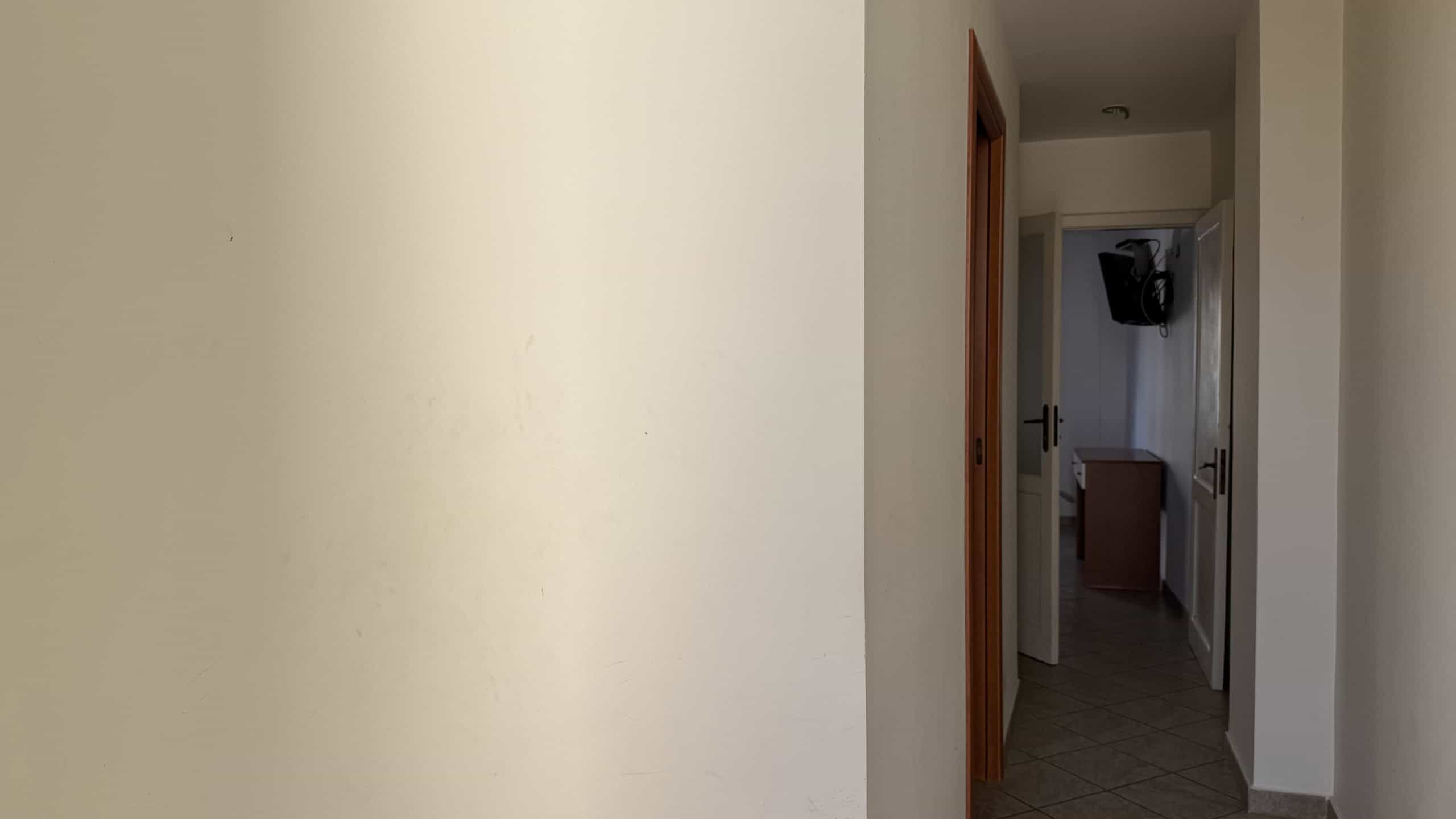 Vista dell'ingresso di un appartamento NextCasa con corridoio e porta aperta, ambiente luminoso e accogliente.