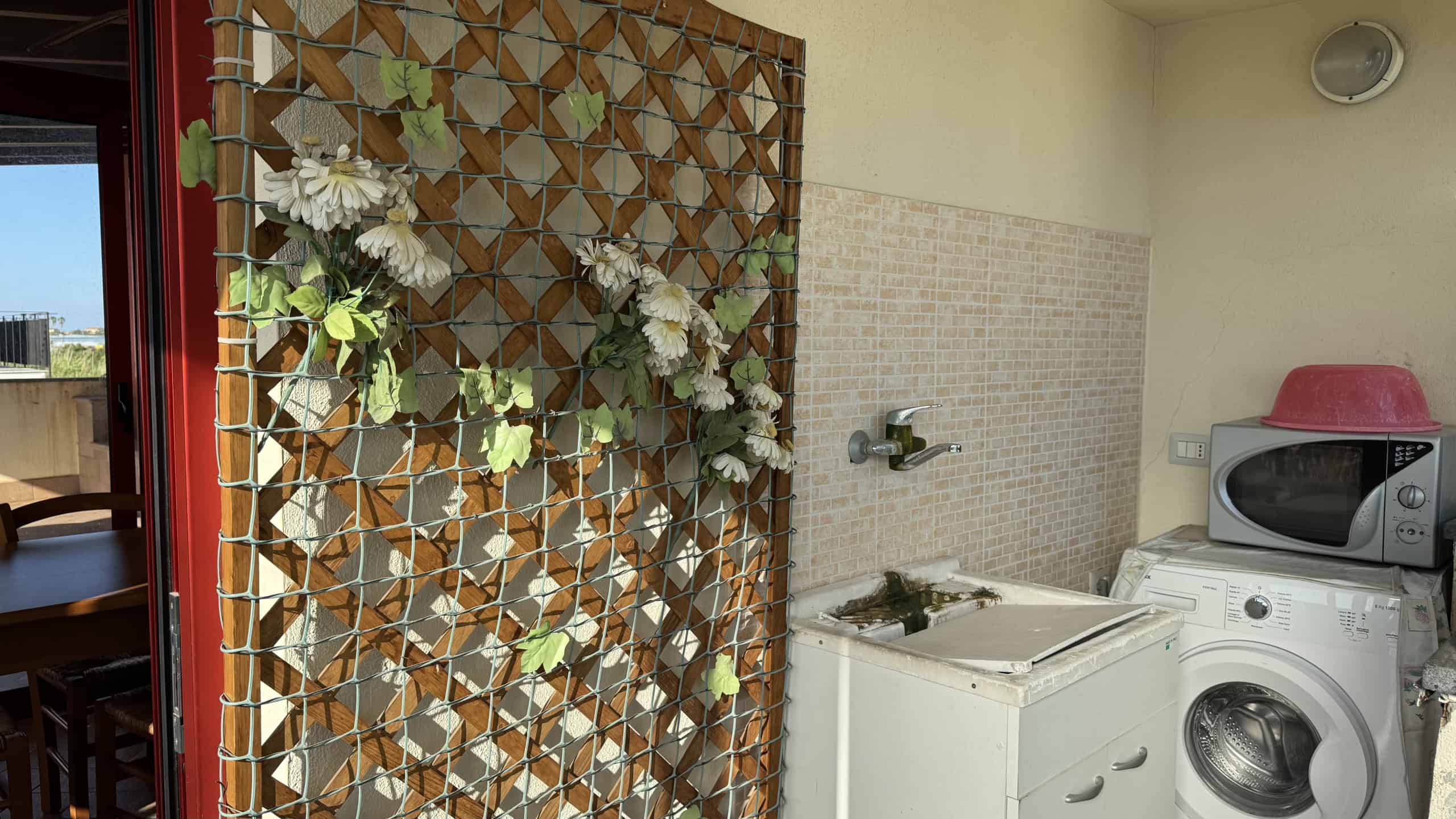 Lavanderia con lavatrice e microonde, spazio funzionale e moderno in appartamento NextCasa, ideale per la gestione quotidiana della casa.