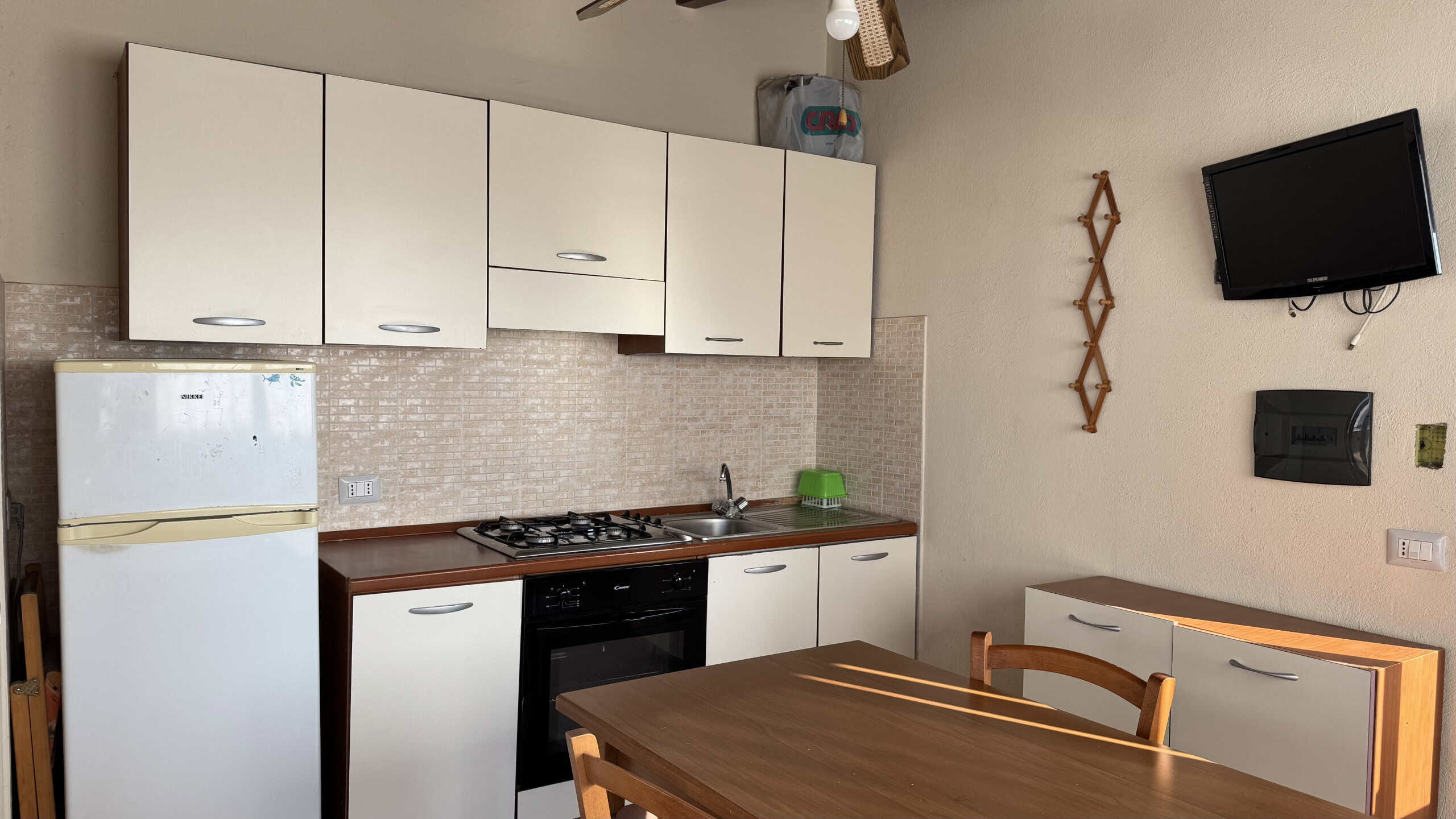 Cucina moderna con elettrodomestici integrati, mobili bianchi e piano di lavoro in legno, ideale per ambienti residenziali. Perfetta per chi cerca funzionalità e stile in cucina.