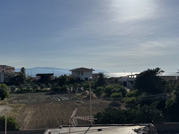 Vista panoramica di case moderne e natura vicino al mare in Italia, con cielo sereno e paesaggio mediterraneo, ideale per immobili residenziali e investimenti immobiliari.