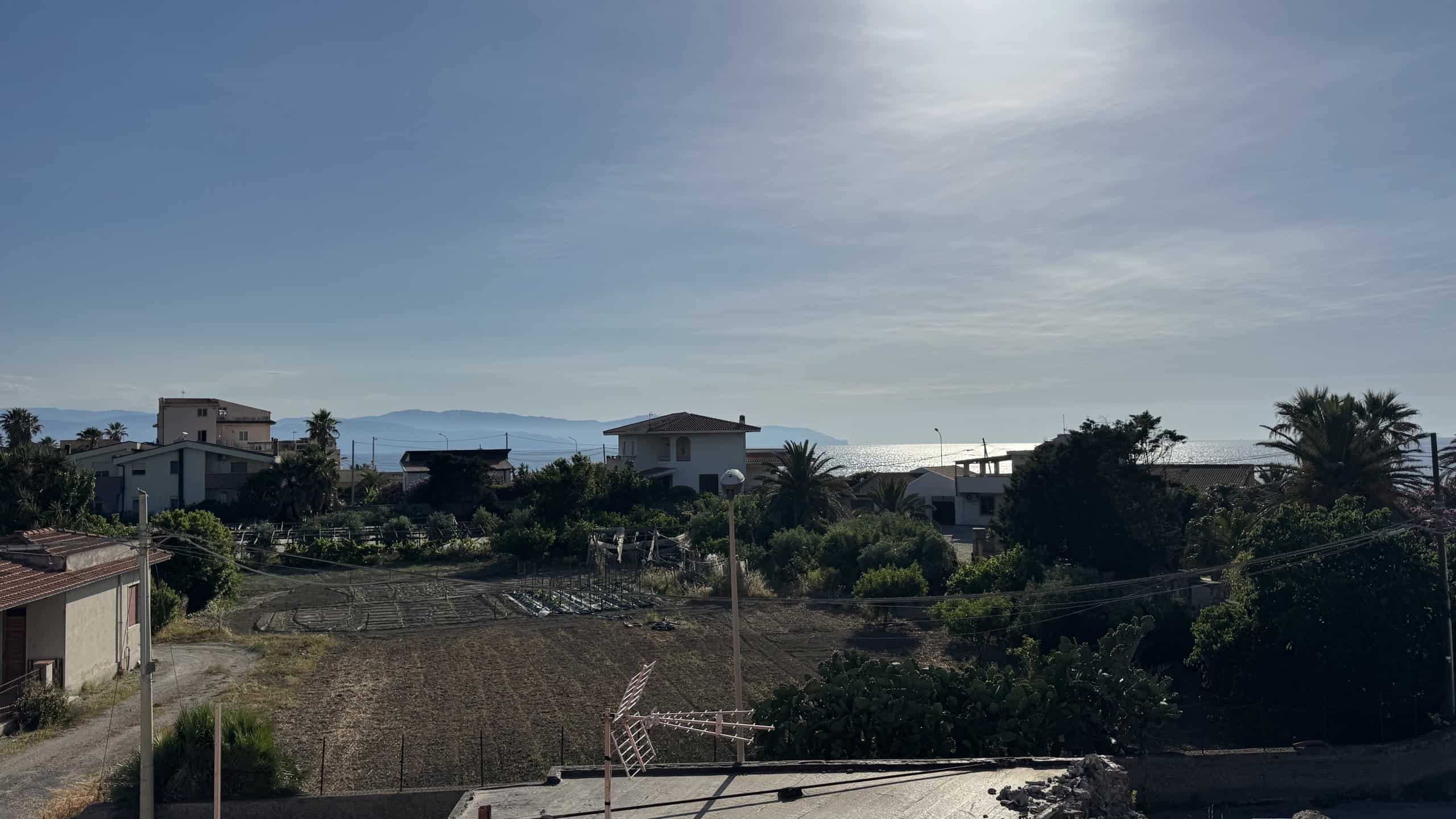 Vista panoramica di case moderne e natura vicino al mare in Italia, con cielo sereno e paesaggio mediterraneo, ideale per immobili residenziali e investimenti immobiliari.