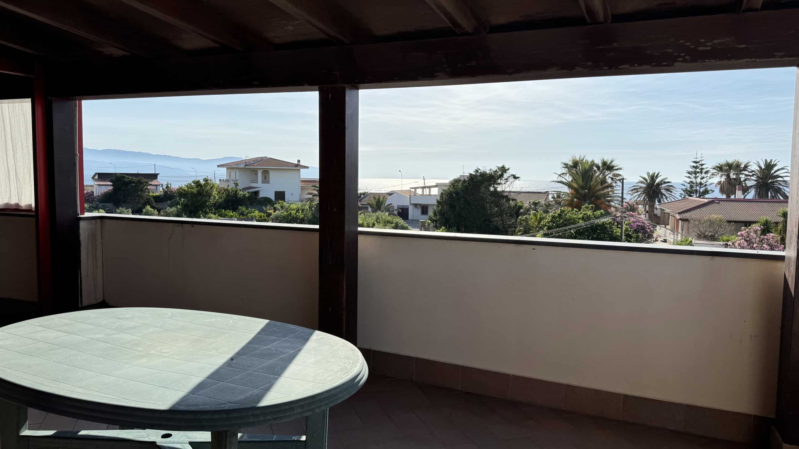 Balcone con vista mare e palme tropicali, spazio esterno ideale per relax e convivialità, in un contesto residenziale vicino alla spiaggia. Perfetto per chi cerca una casa con vista e comfort all'aper.