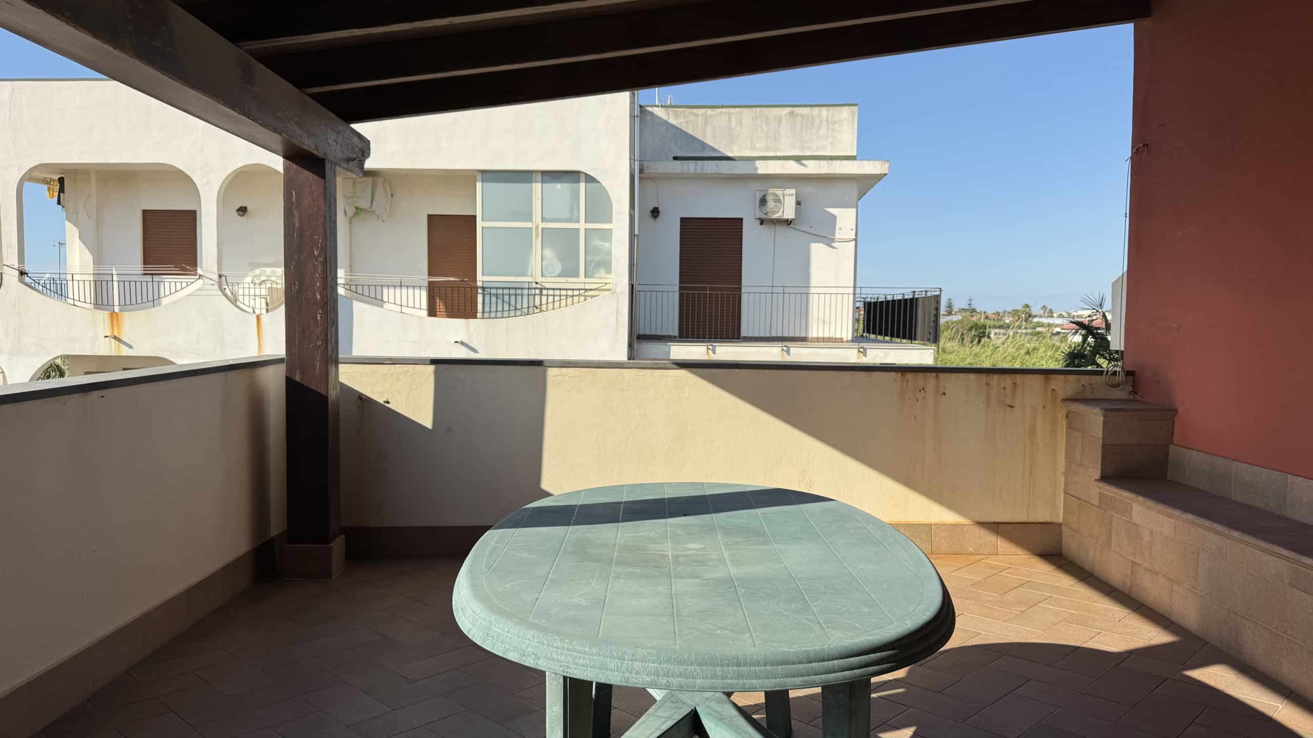 Balcone con tavolo rotondo in ceramica e vista sulla città, ideale per relax e cene all'aperto. Spazio esterno con protezione solare, perfetto per godersi il panorama e momenti di convivialità.