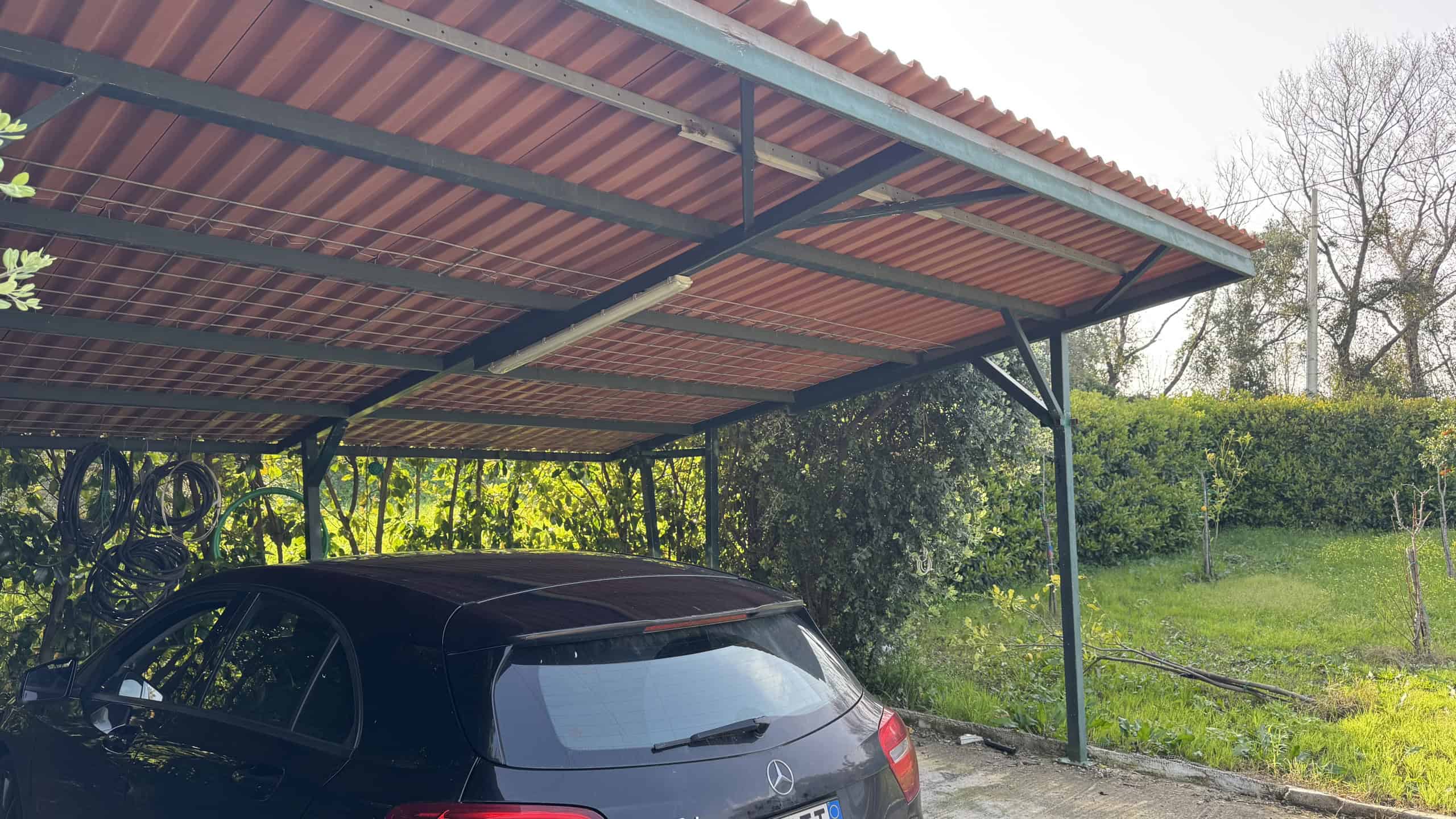 Garage coperto con tetto in metallo e spazio per un'auto, situato in un'area verde a Corriolo, vicino a Villa unifamiliare in vendita.