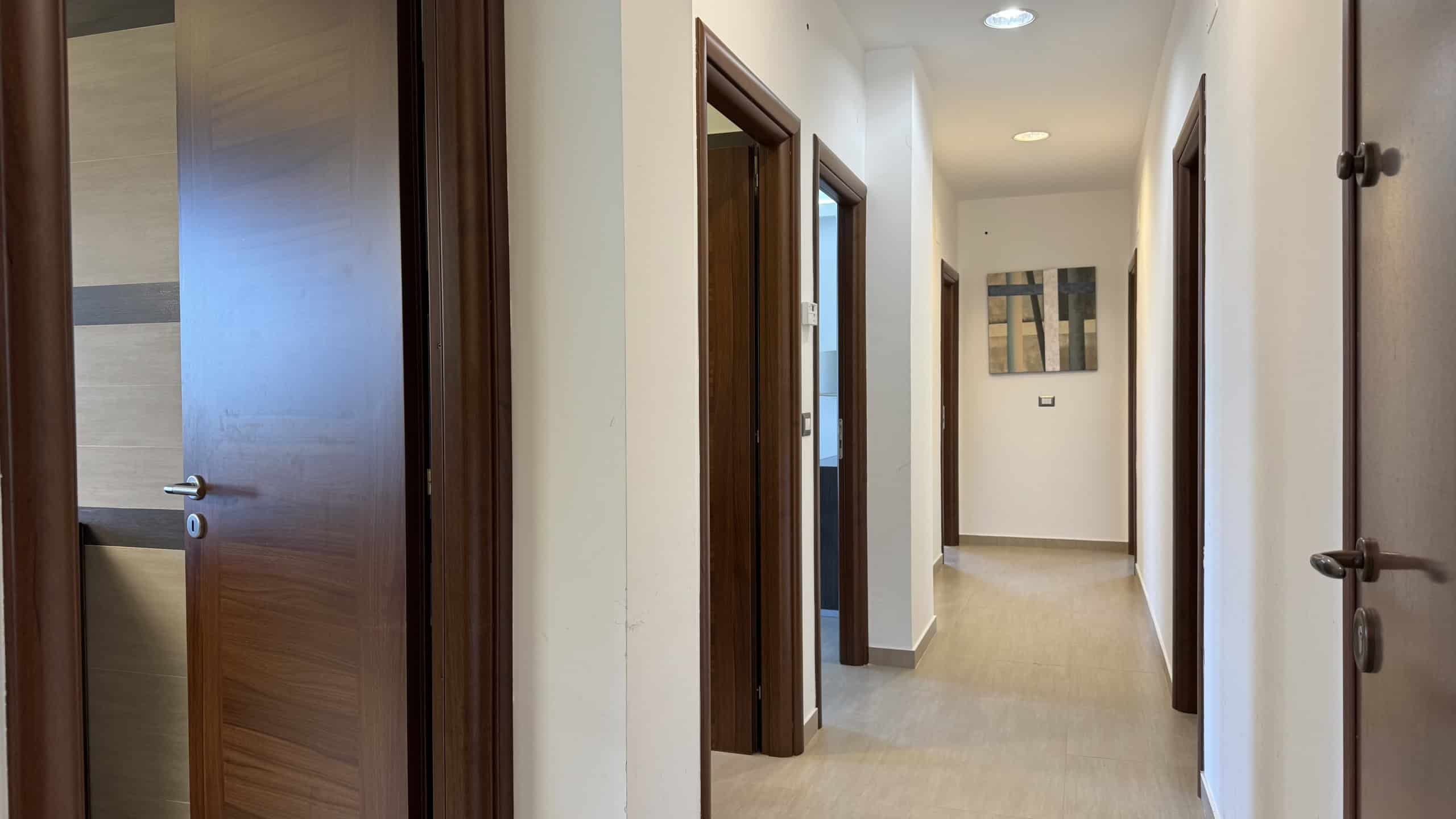 Immagine di un corridoio interno di una villa unifamiliare in vendita a Corriolo, con pareti bianche e porte in legno scuro.